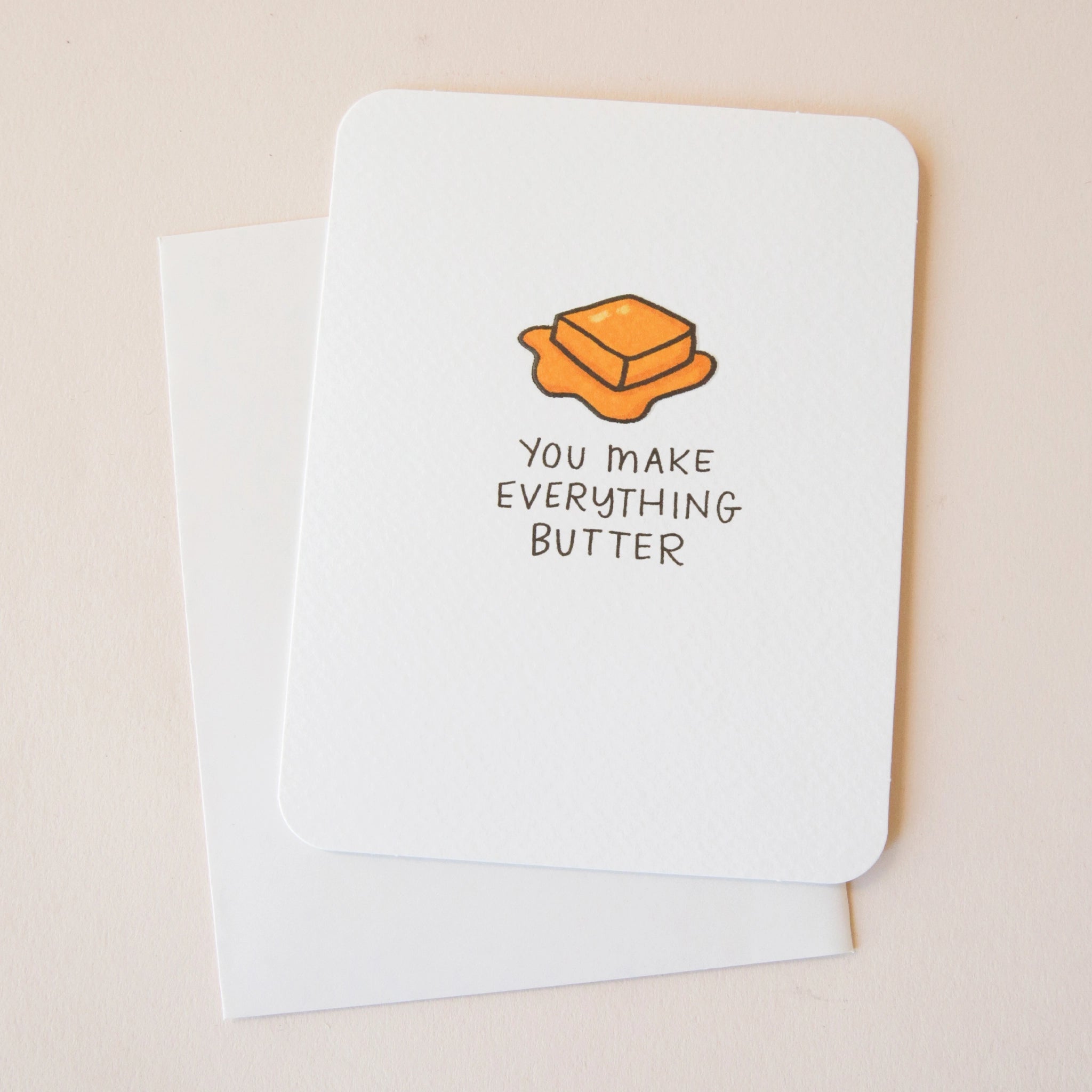 A white card with a slice of yellow butter graphic and black text that reads &quot;You Make Everything Butter&quot; along with a coordinating sticker that is included and has bubble edges and has a similar butter illustration and says, &quot;To My Butter Half&quot;.