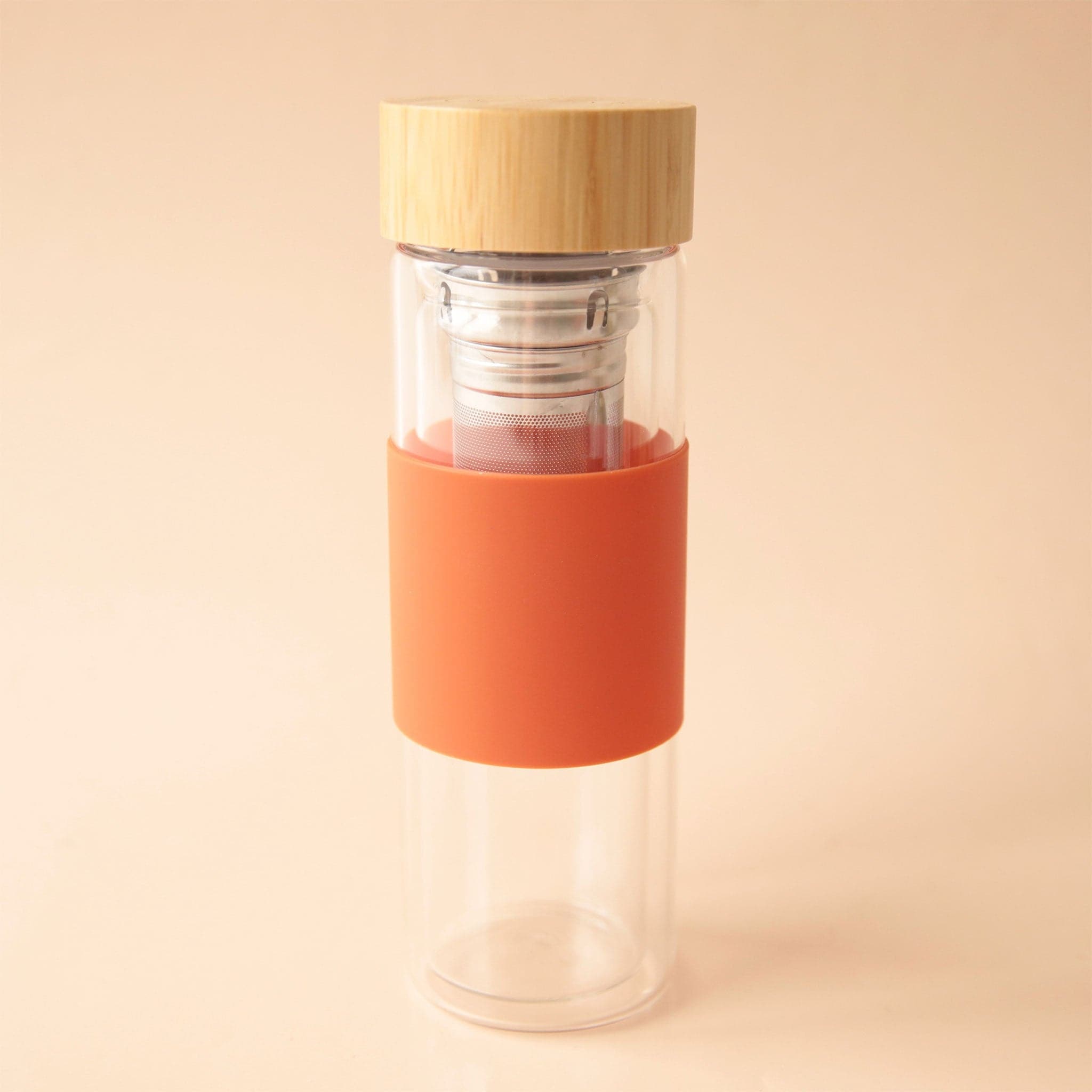 A glass infusing travel cup with a bamboo lid and an orange silicone sleeve.