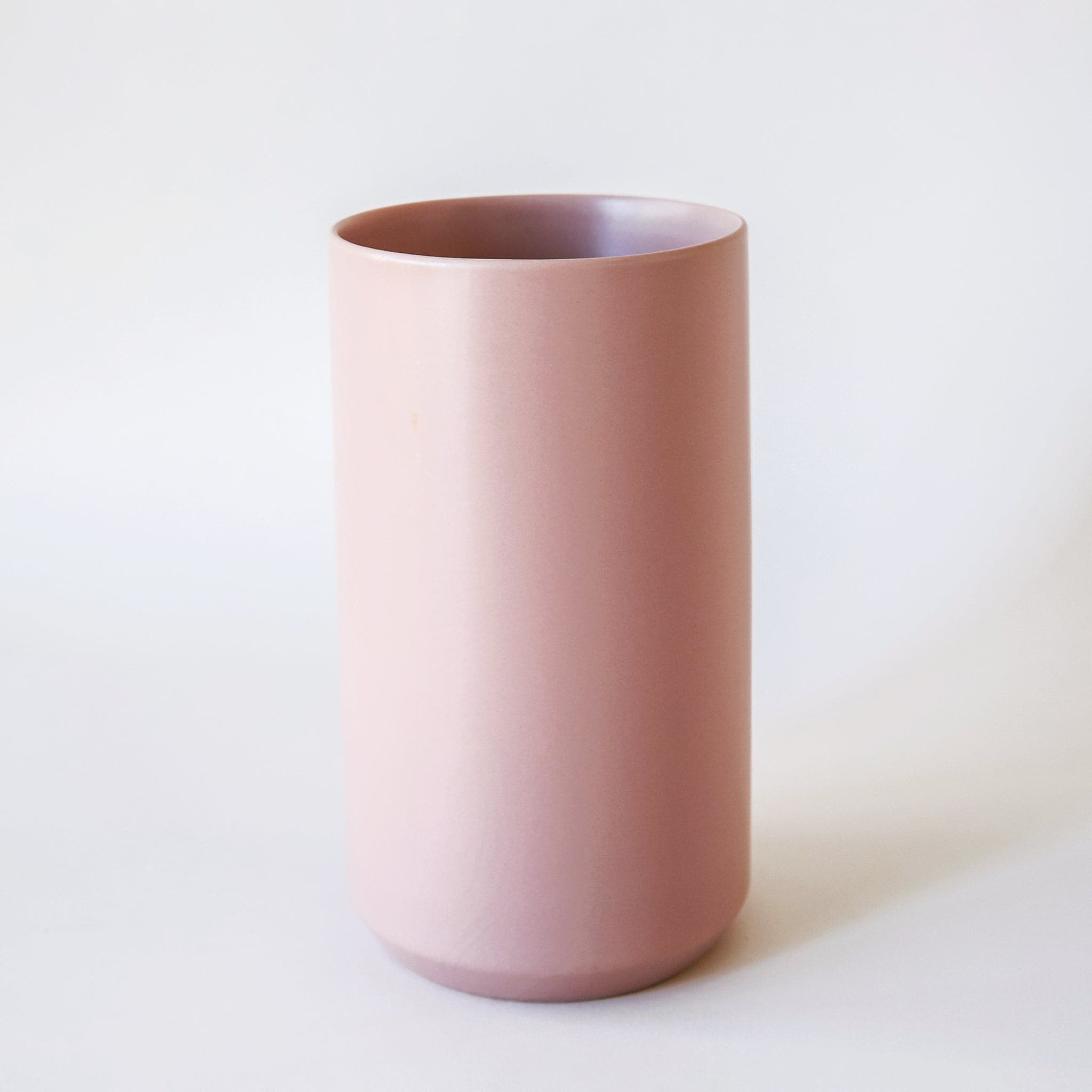 A tall, matte pink cylindrical vase.