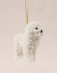 A cream furry poodle ornament with a gold loop for hanging.