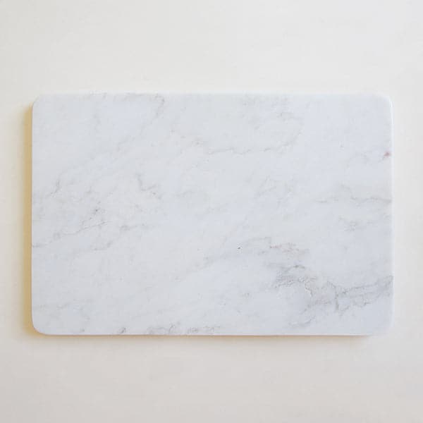 On a white background is a white marble cheese board. 