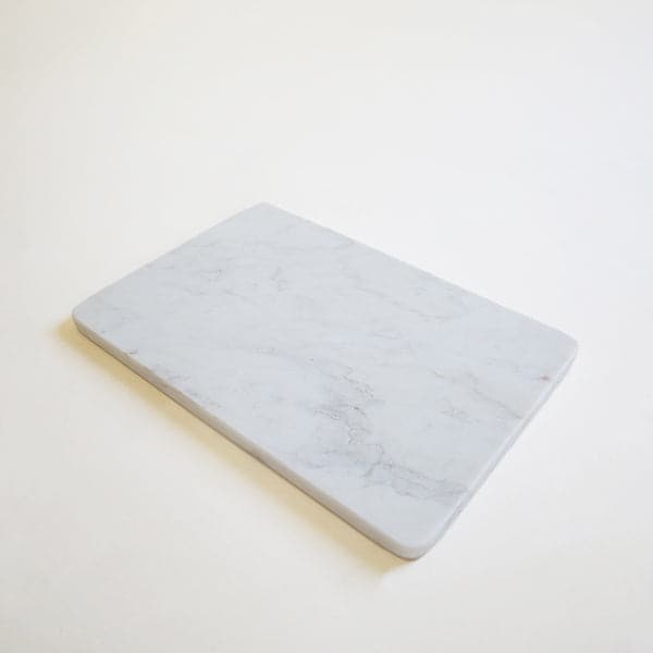 On a white background is a white marble cheese board.
