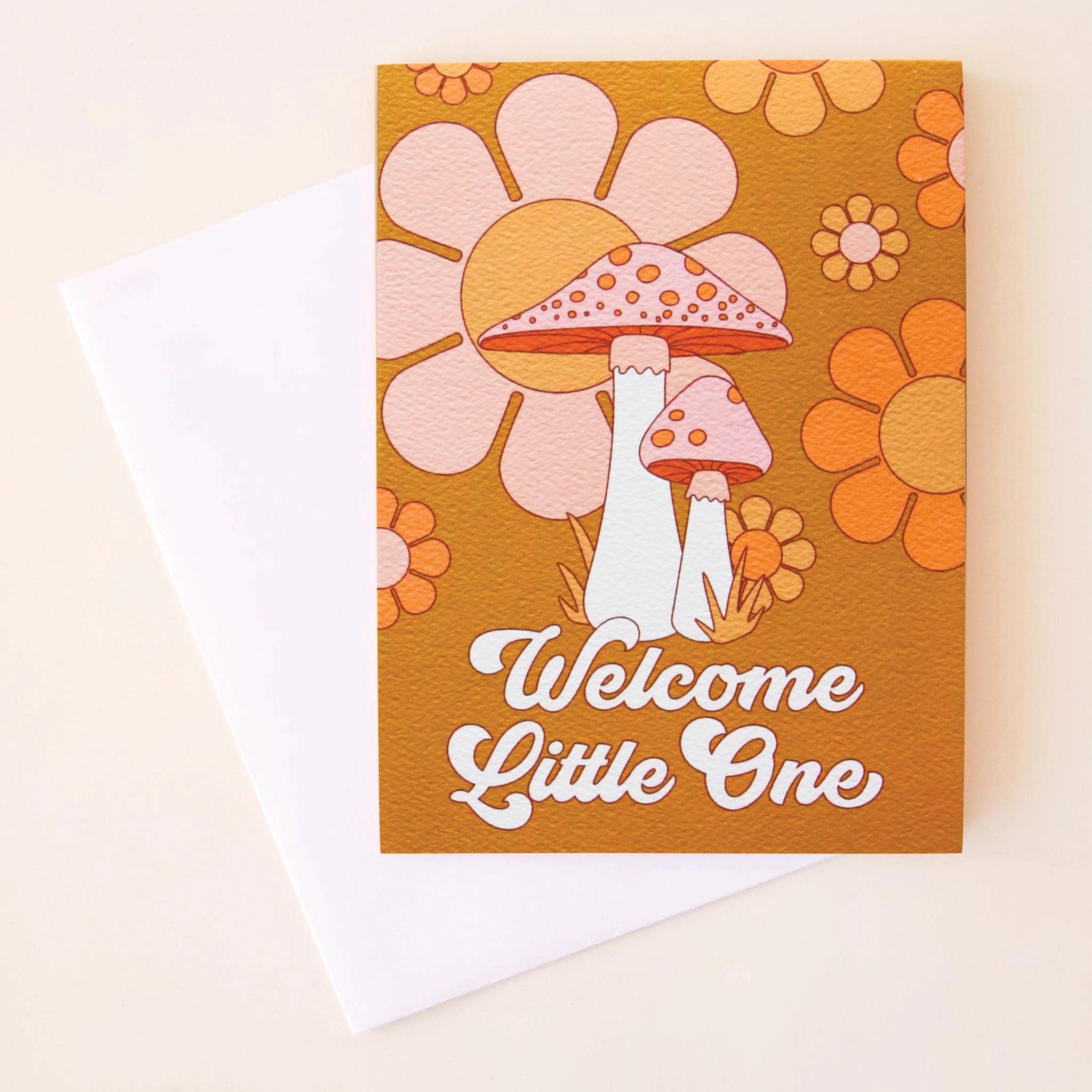 On a cream background is an orange card with a floral and mushroom design along with white text that reads, "Welcome Little One".