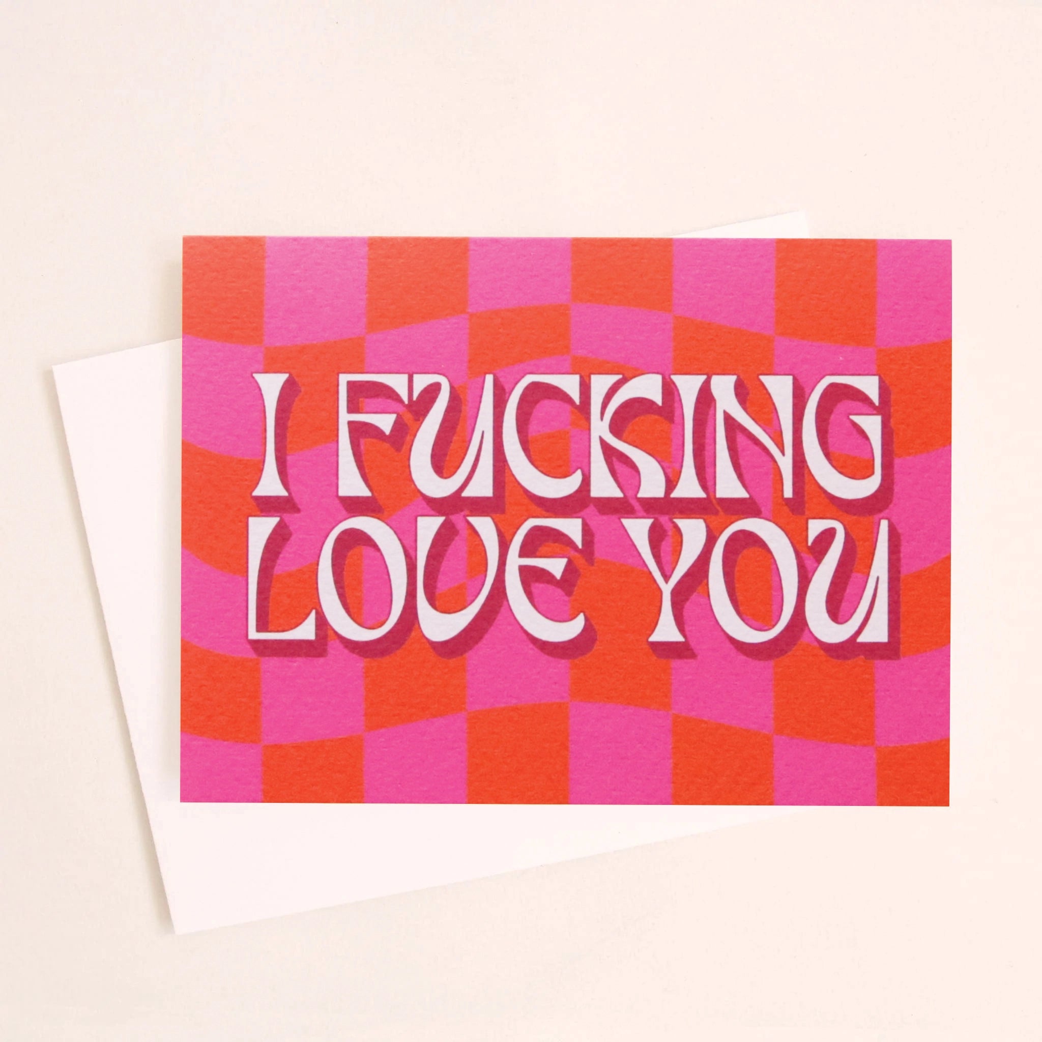 On a white background is a hot pink and red greeting card what reads, &quot;I Fucking Love You&quot; in light pink letters, and photographed with the coordinating white envelope. 