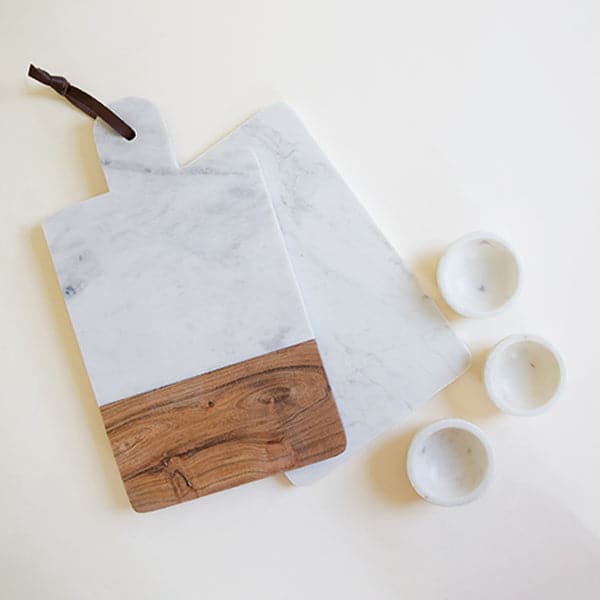 On a white background is a white marble cheese board staged with a marble and wood cheese board. 
