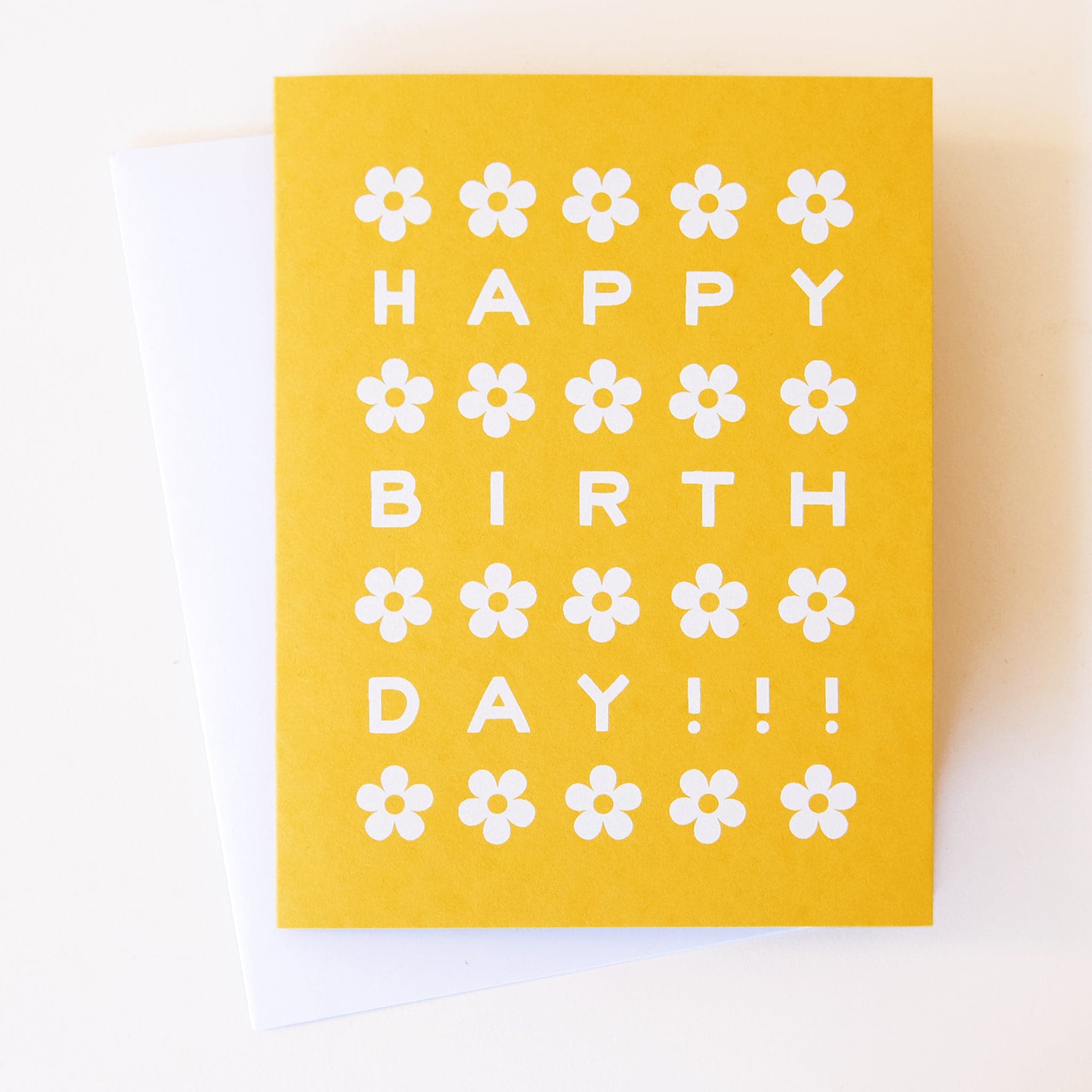 A bright gold card featuring white illustrated daisies and text reading &quot;Happy Birthday!!!&quot; in-between each row of daisies.