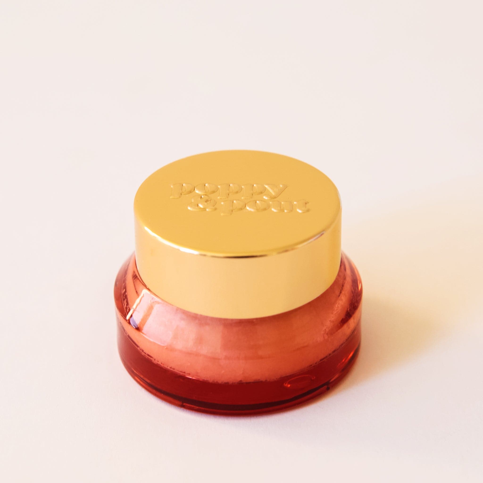 Lip scrub in an orange red container with a gold lid. This lip scrub is grainy, hydrating and perfect for your lips.