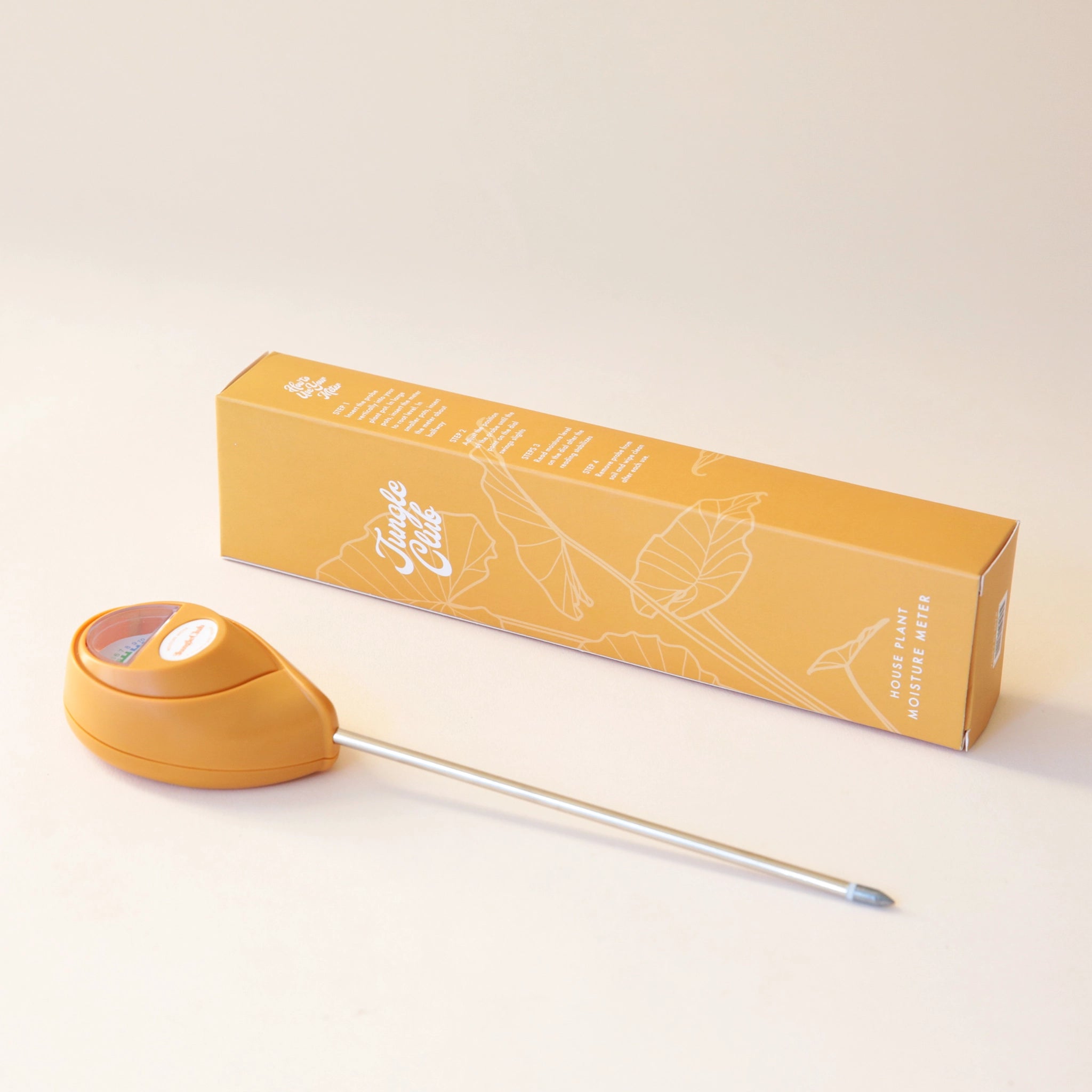 An orange moisture meter with a rounded head and a white meter that ranges from dry, moist, or wet along with a small oval label in the front that reads, "Jungle Club".