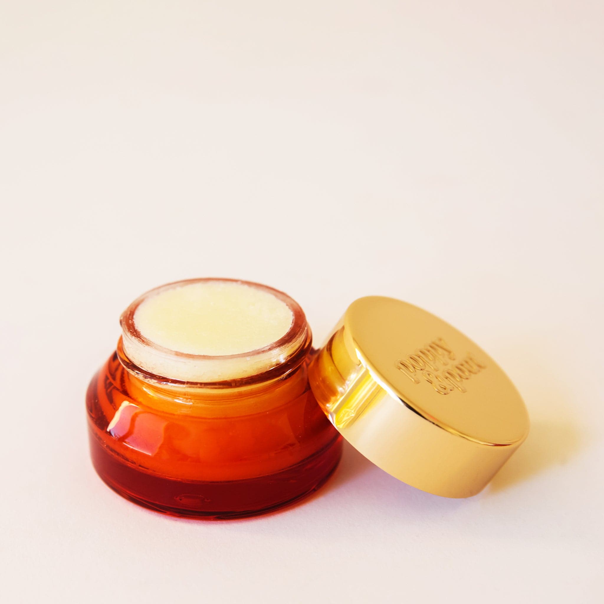 Lip scrub in a dark orange colored container with a gold lid. This lip scrub is grainy, hydrating and perfect for your lips.