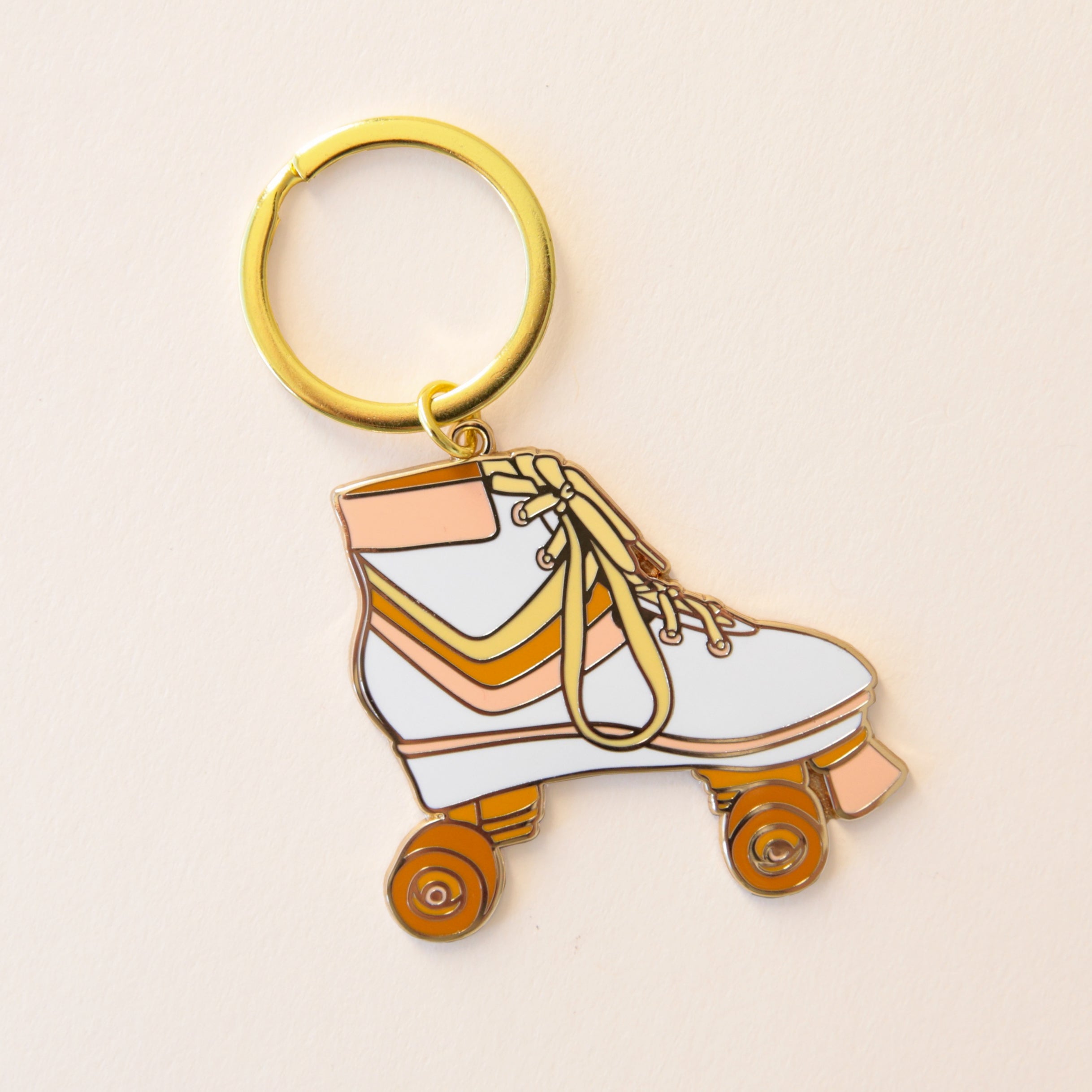 A metal roller skate keychain with orange wheels, and a white boot with pink, orange and yellow stripes in the center along with yellow shoelaces and a gold  keychain hoop.