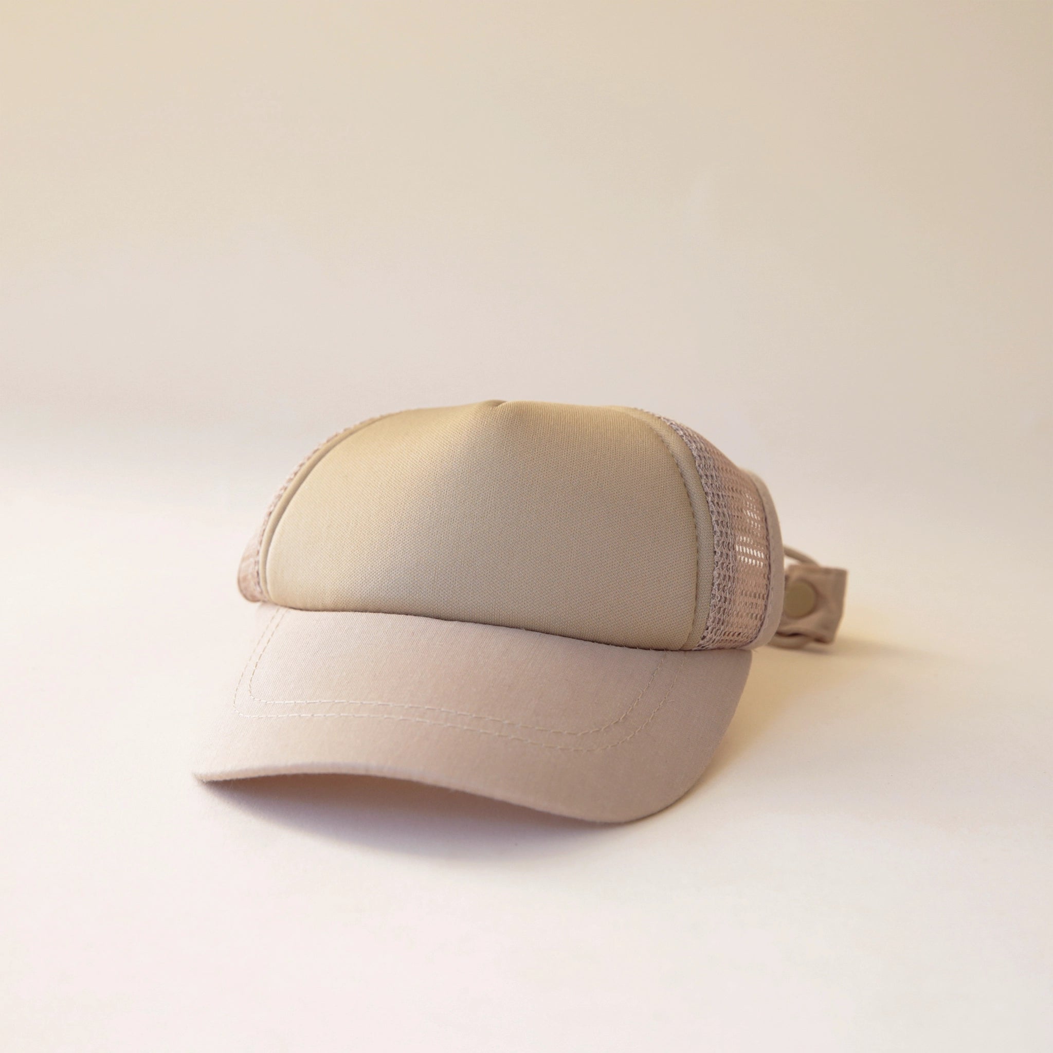 A beige dog baseball hat with a mesh backing.