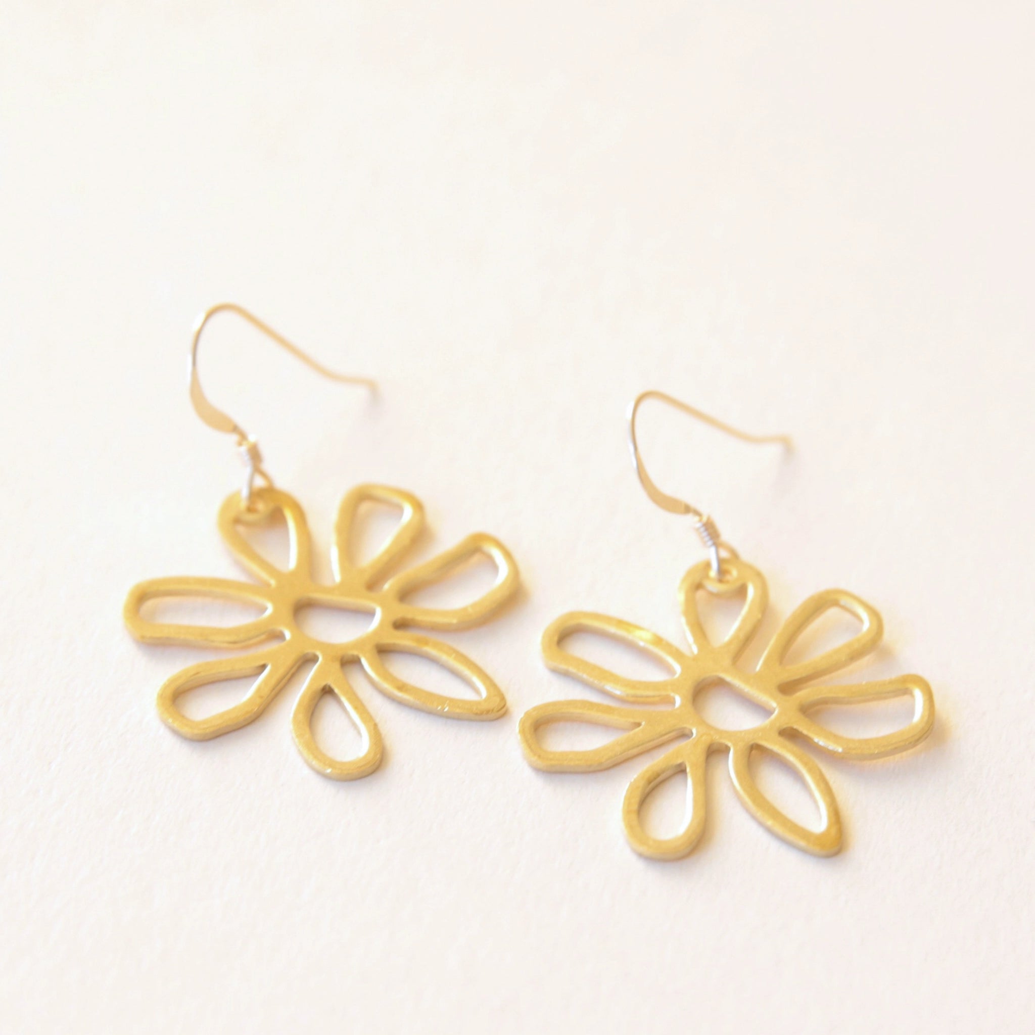 Gold hook earrings with a gold outline flower design.