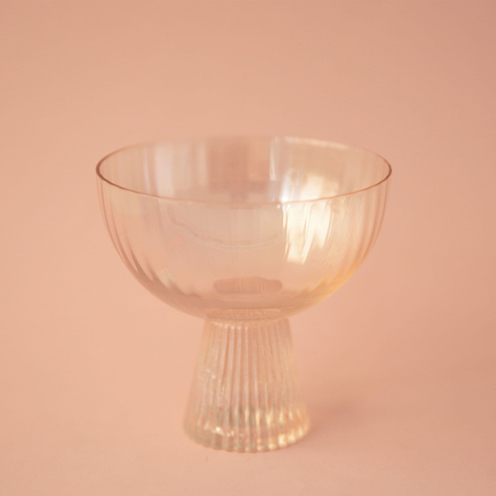A light peach coupe glass with a thick ribbed base.