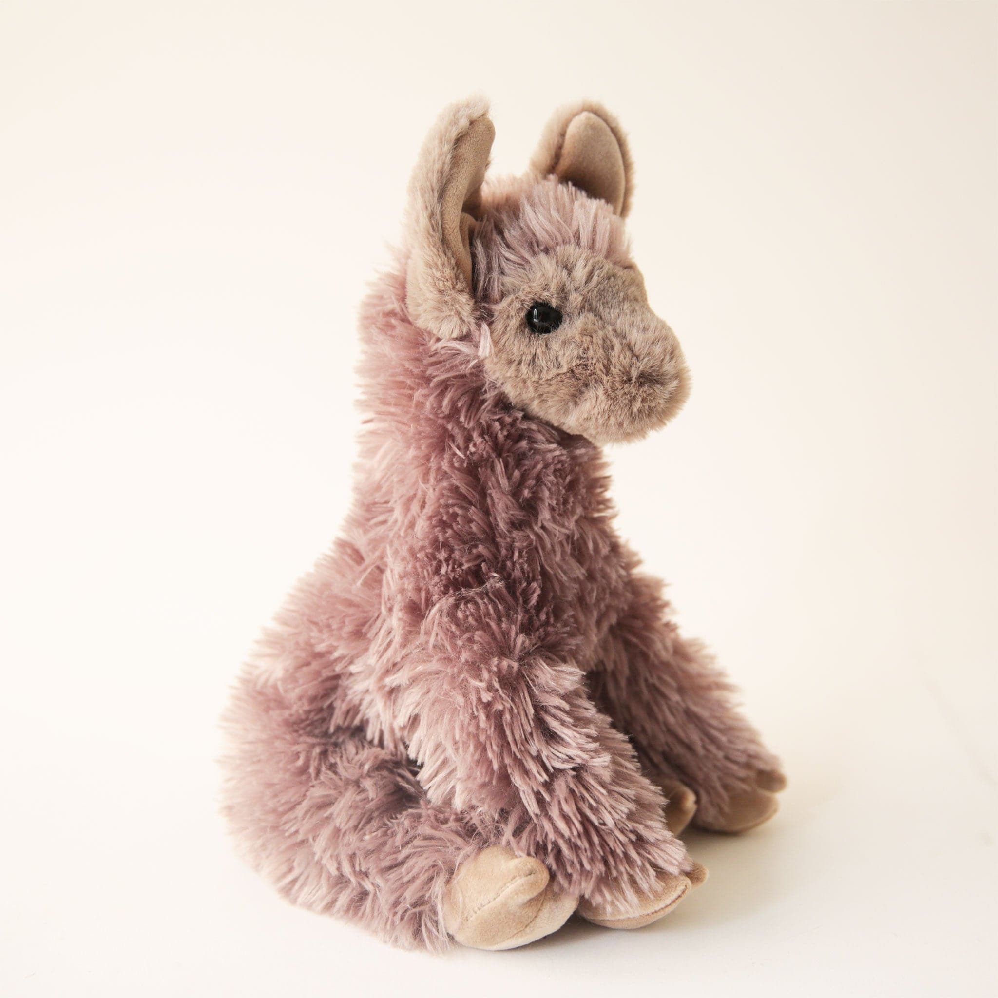 A super fuzzy llama with taupe colored fur and a relaxed posture perfect for snuggling. 