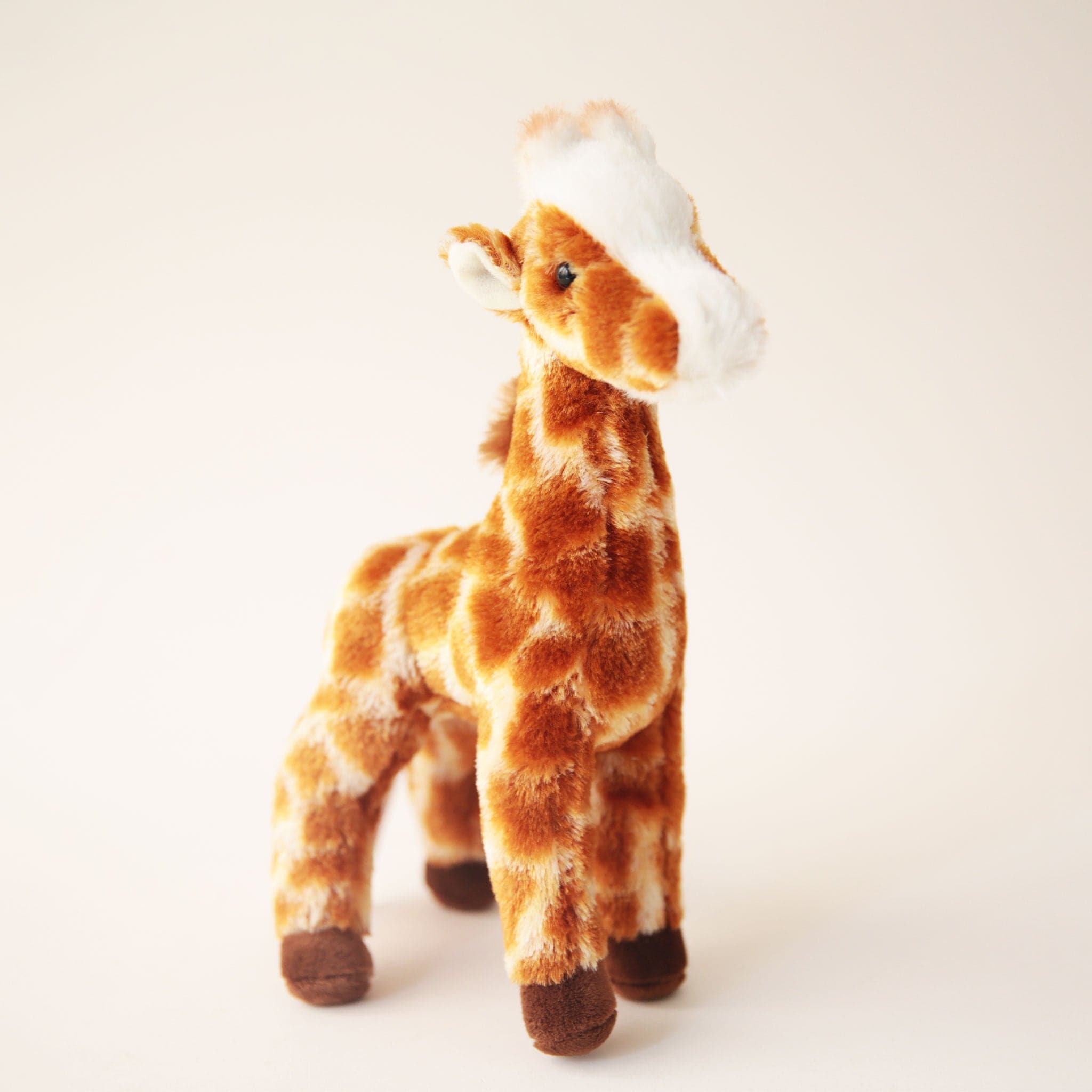 A brown and white giraffe stuffed animal toy with chocolate brown hooves. 