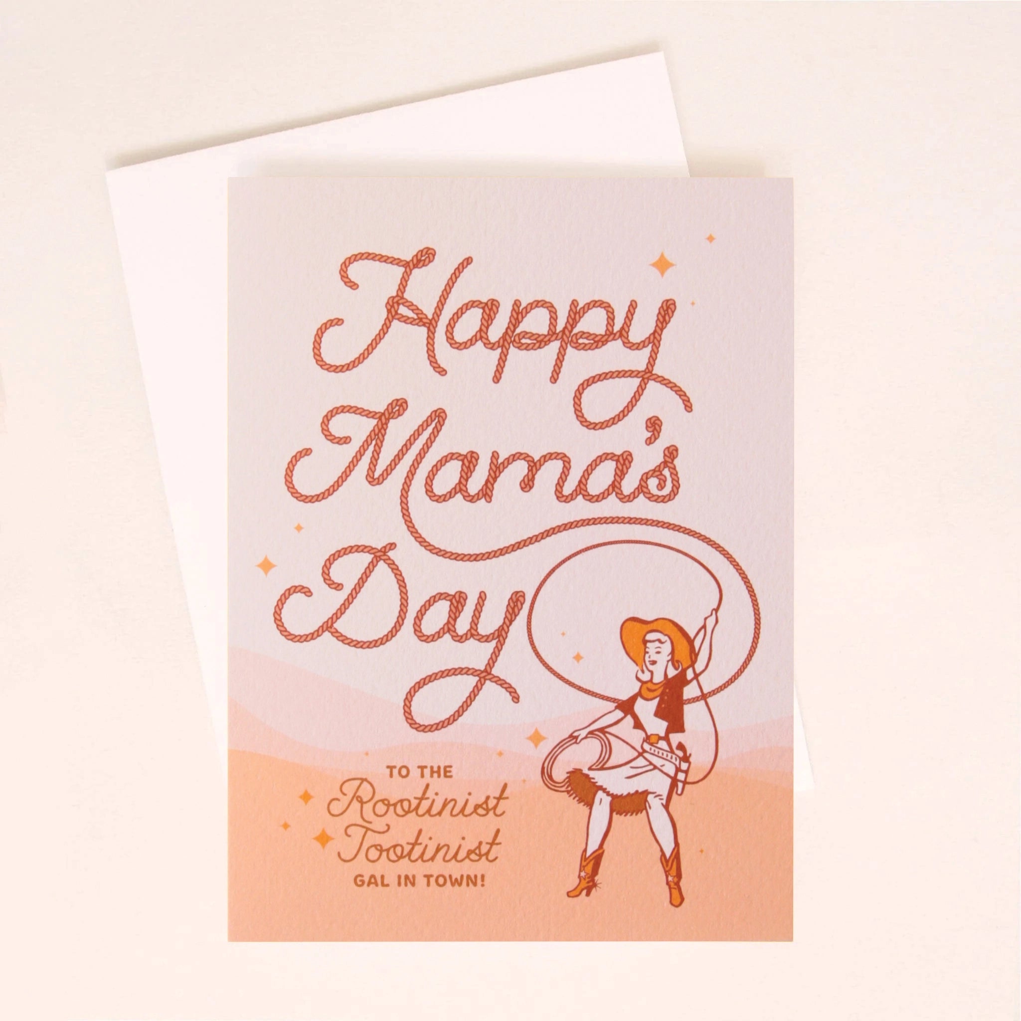 A light pink gradient card with text that reads, "Happy Mama's Day" in a rope font with an illustration of a cowgirl in the bottom right corner as well as more text that reads, "To The Rootinist Tootinist Gal In Town!" in brown cursive letters.
