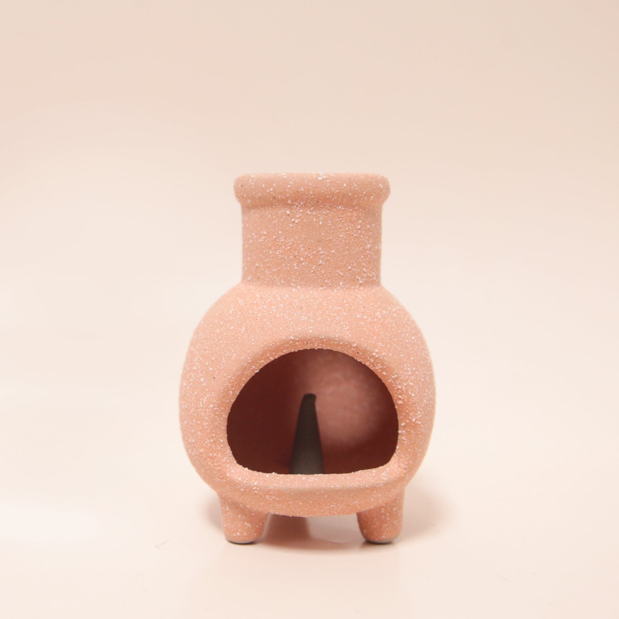 A tiny terracotta chiminea with legs and an opening for the incense cones to sit inside.