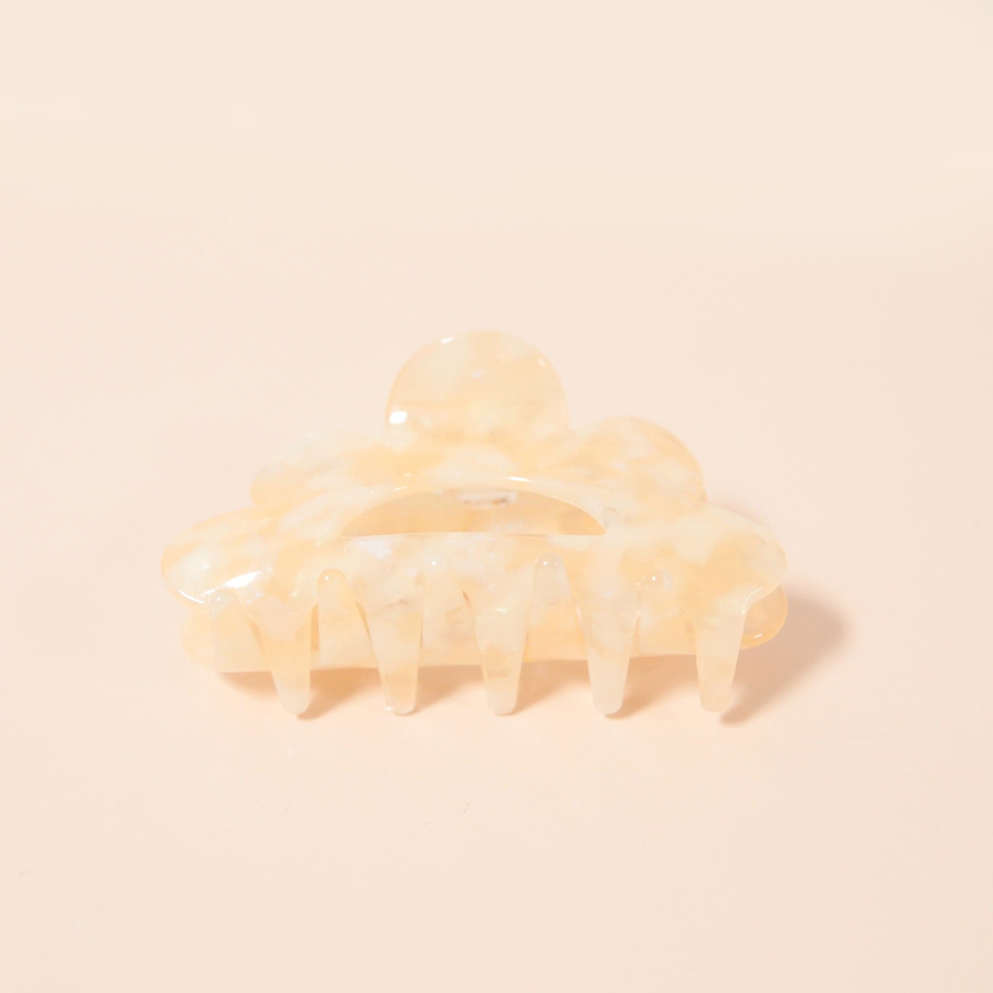 An ivory claw clip with a scalloped edge detail and an ivory and white color.