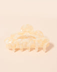 An ivory claw clip with a scalloped edge detail and an ivory and white color.