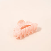 A scalloped peach hair clip made of durable plastic.