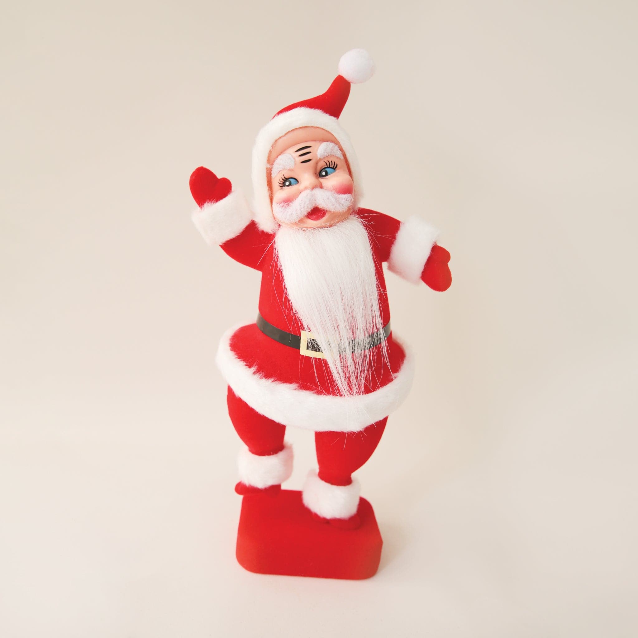 A plastic Santa figurine with a red suit and furry detailing on the cuffs, jacket and hat.