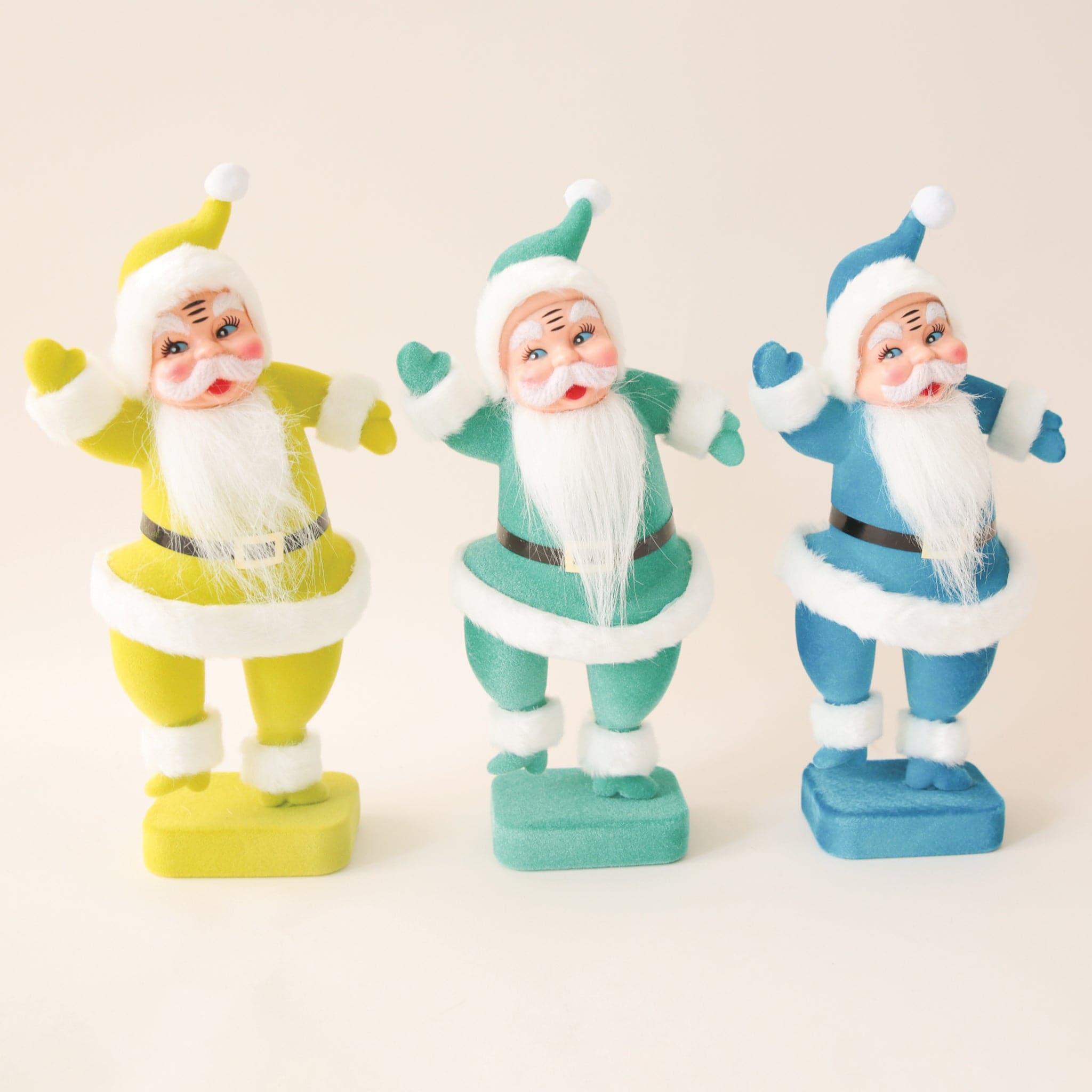 A plastic Santa figurine with a teal suit on with fuzzy cuffs and hat next to all the other colors available.