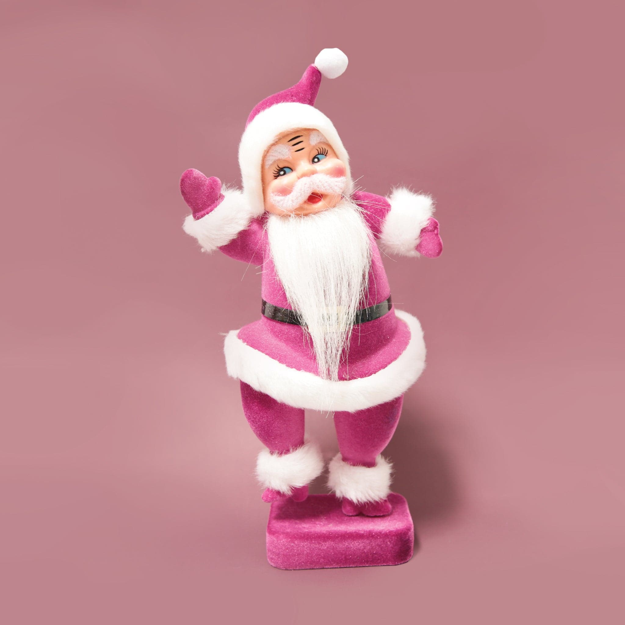 A plastic Santa figurine with a violet suit on.