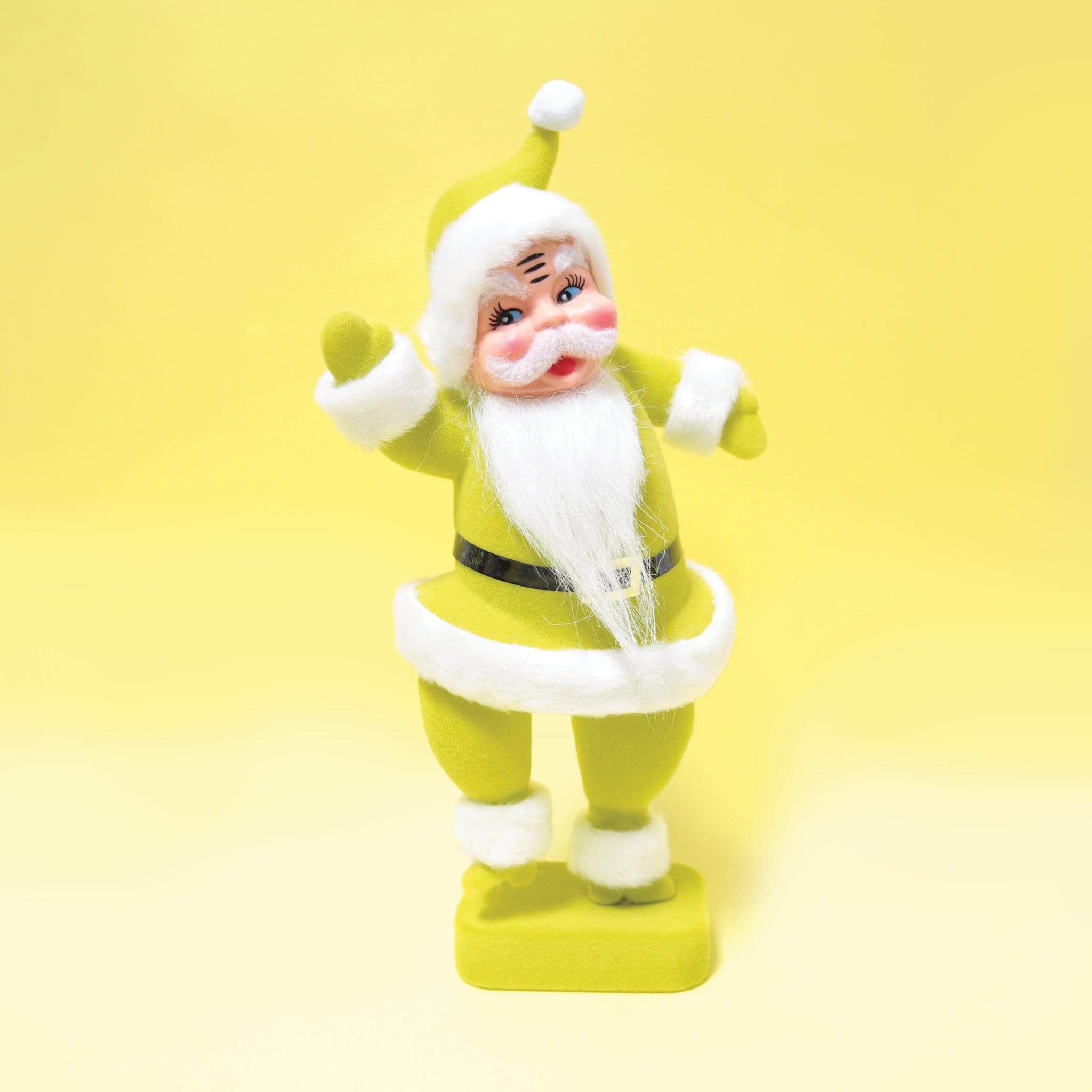A plastic santa figurine with a chartreuse suit on with furry detailing the cuffs, jacket and hat.