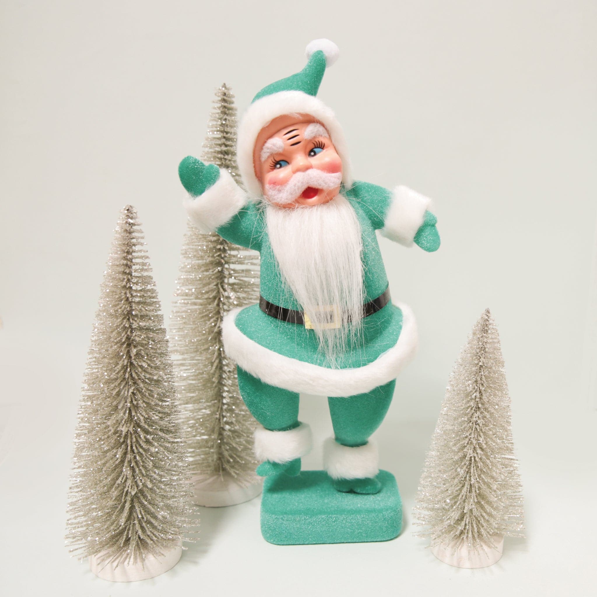A plastic Santa figurine with a teal suit on with fuzzy cuffs and hat.