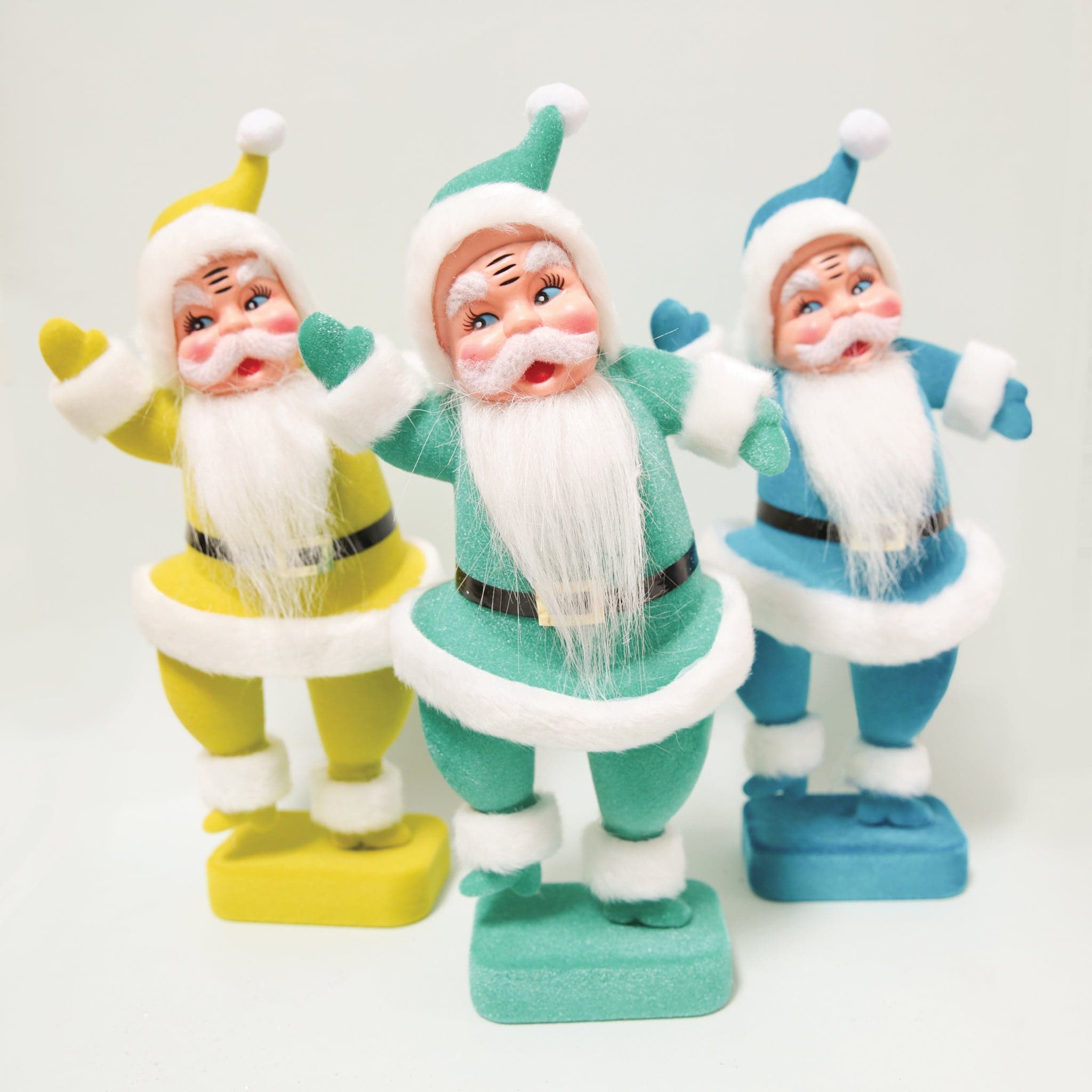 A plastic Santa figurine with a teal suit on with fuzzy cuffs and hat next to all the other colors available.