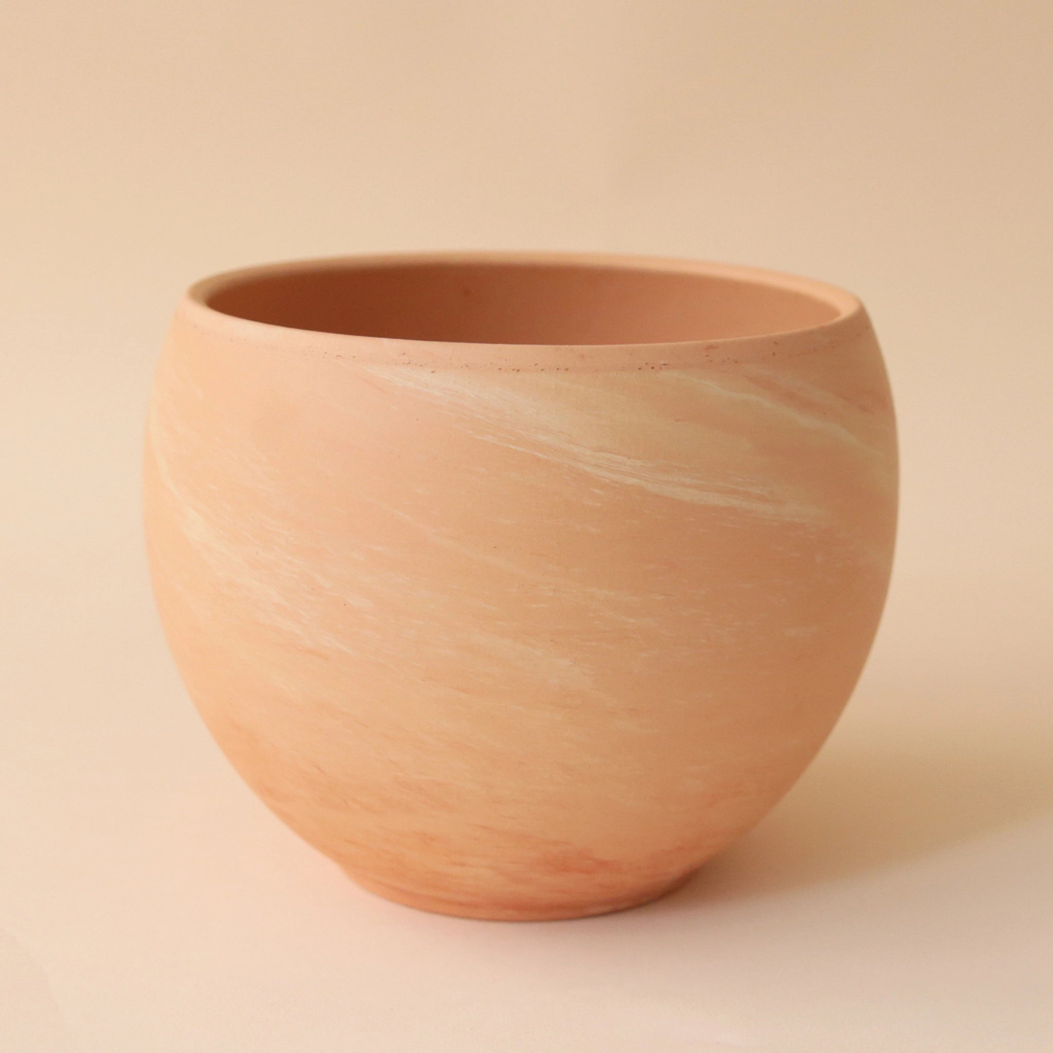 On a peach background is a terracotta circle planter.