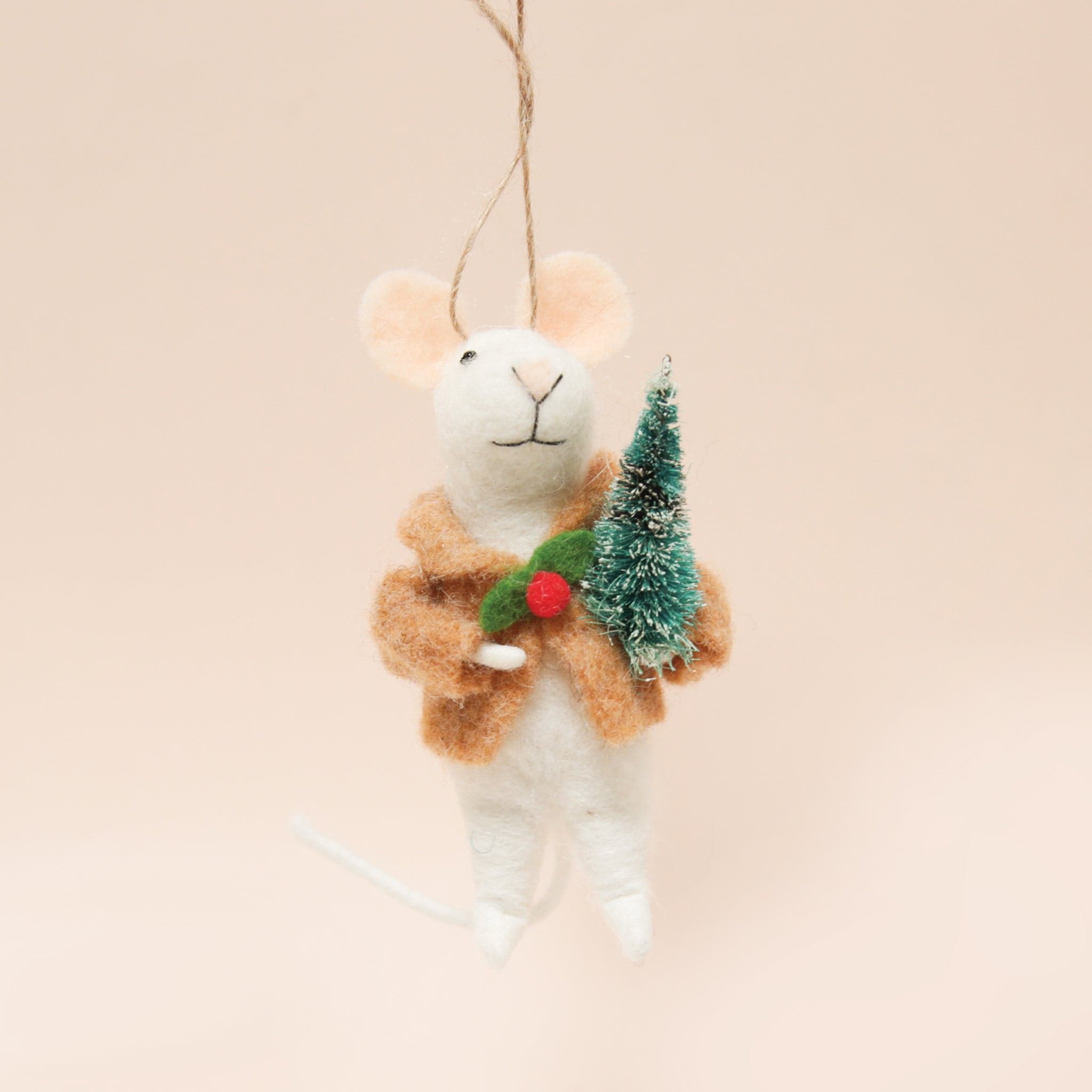 A white felt mouse ornament with a tan jacket on that has holly as the button and holding a small green bristle tree.