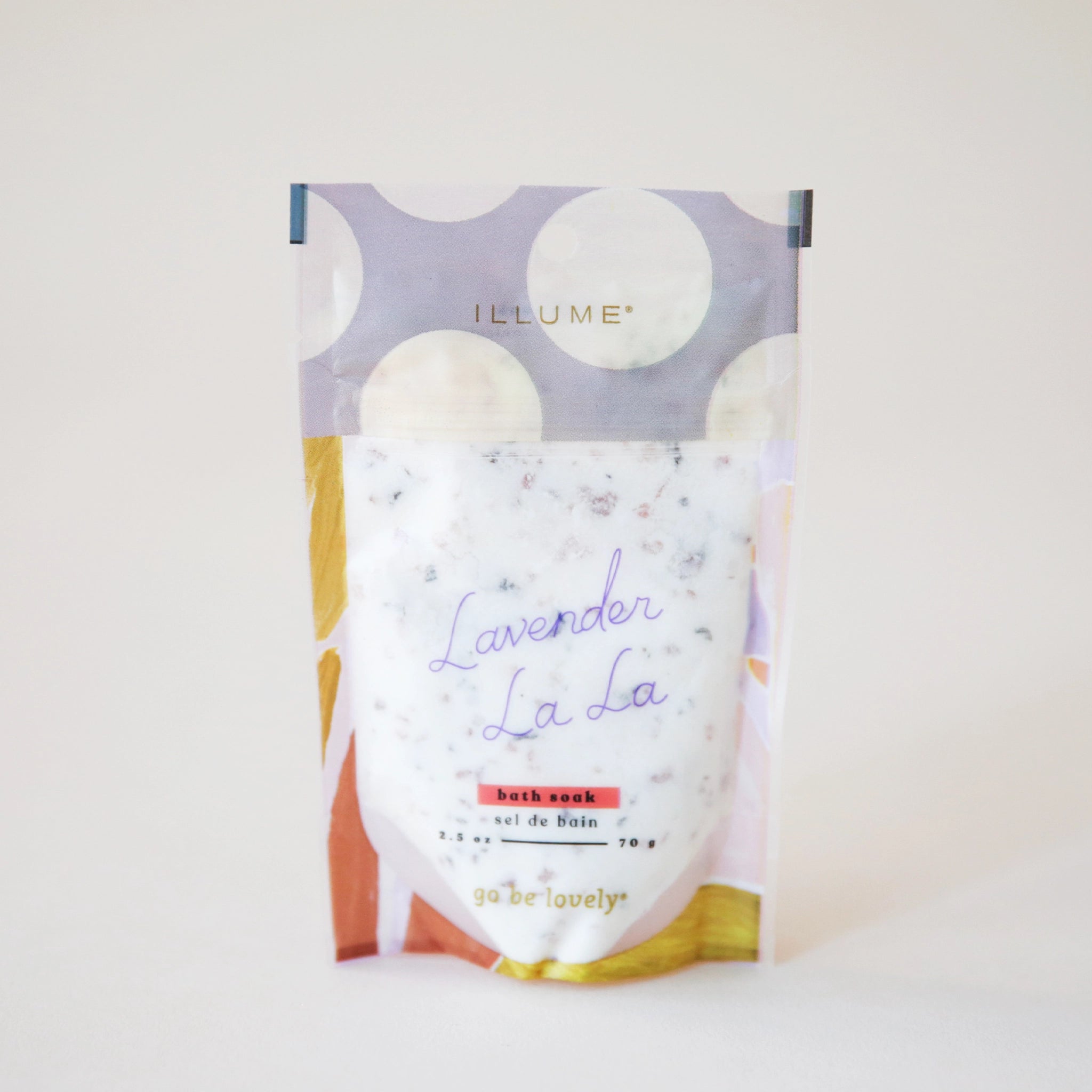 A bag of lavender scented bath soak, featuring a lavender and cream polka dot bag along with accents of yellow and rust and text on the front that reads, "Lavender La La Bath Soak".