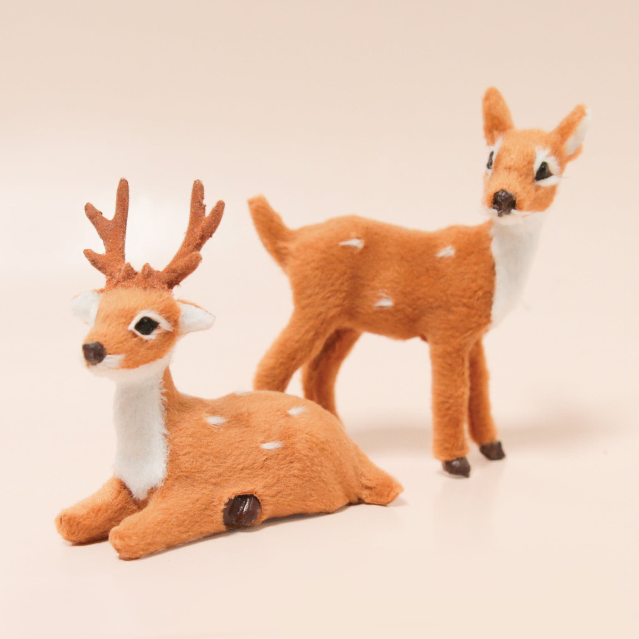 A brown faux fur covered seated reindeer buck figure rests in front of a matching fawn figure.