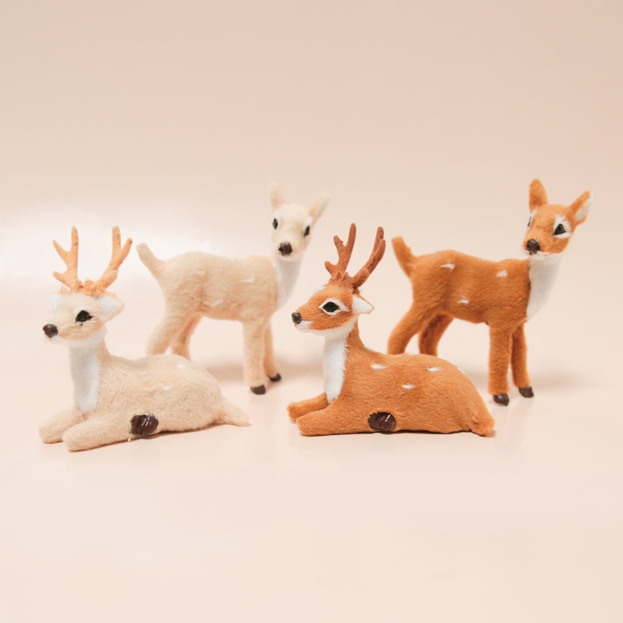 A variety of reindeer figures in brown and cream rest on a light peach background