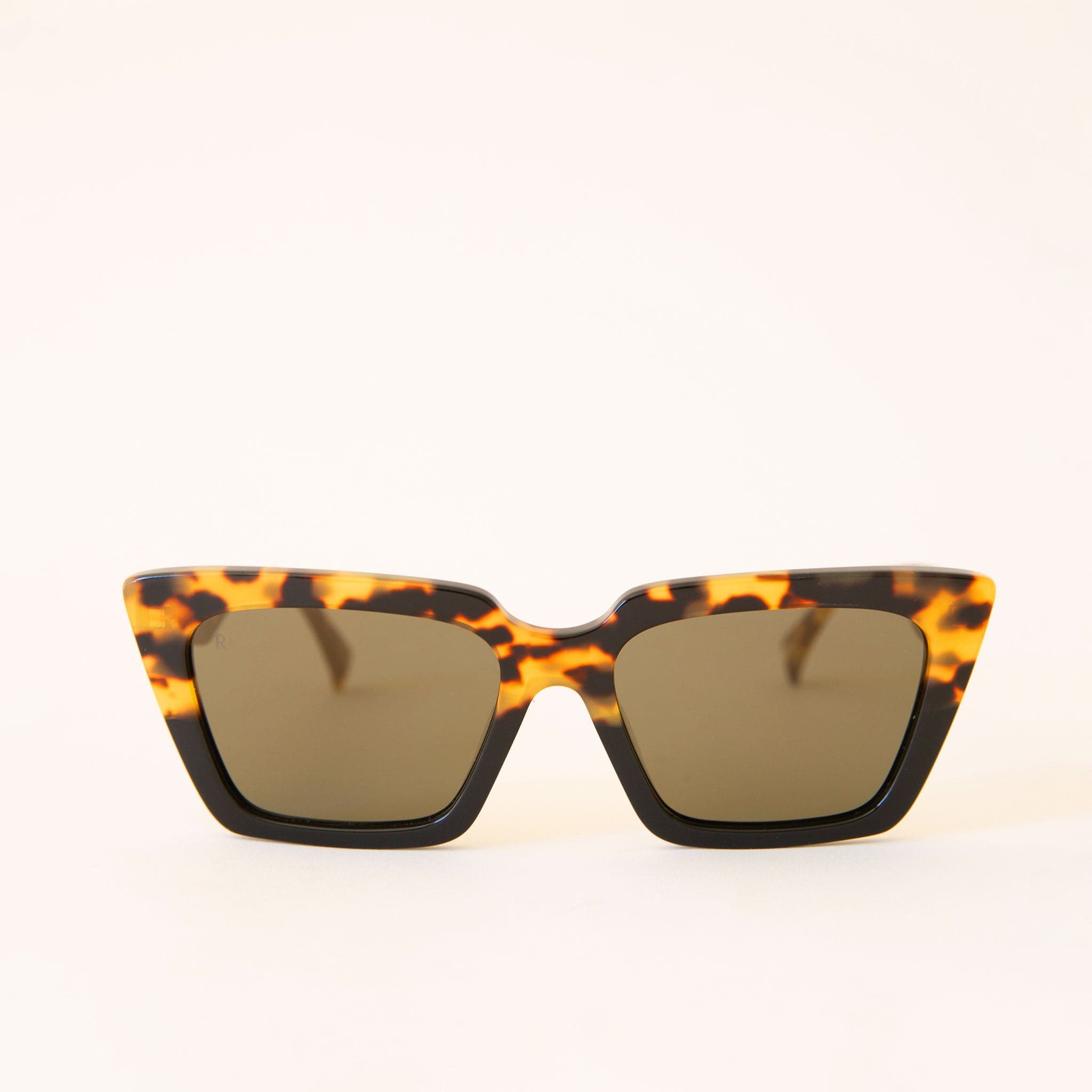 Pair of two toned tortoise and black sunglasses with a geometric cat eye frame shape and dark grey lenses. 