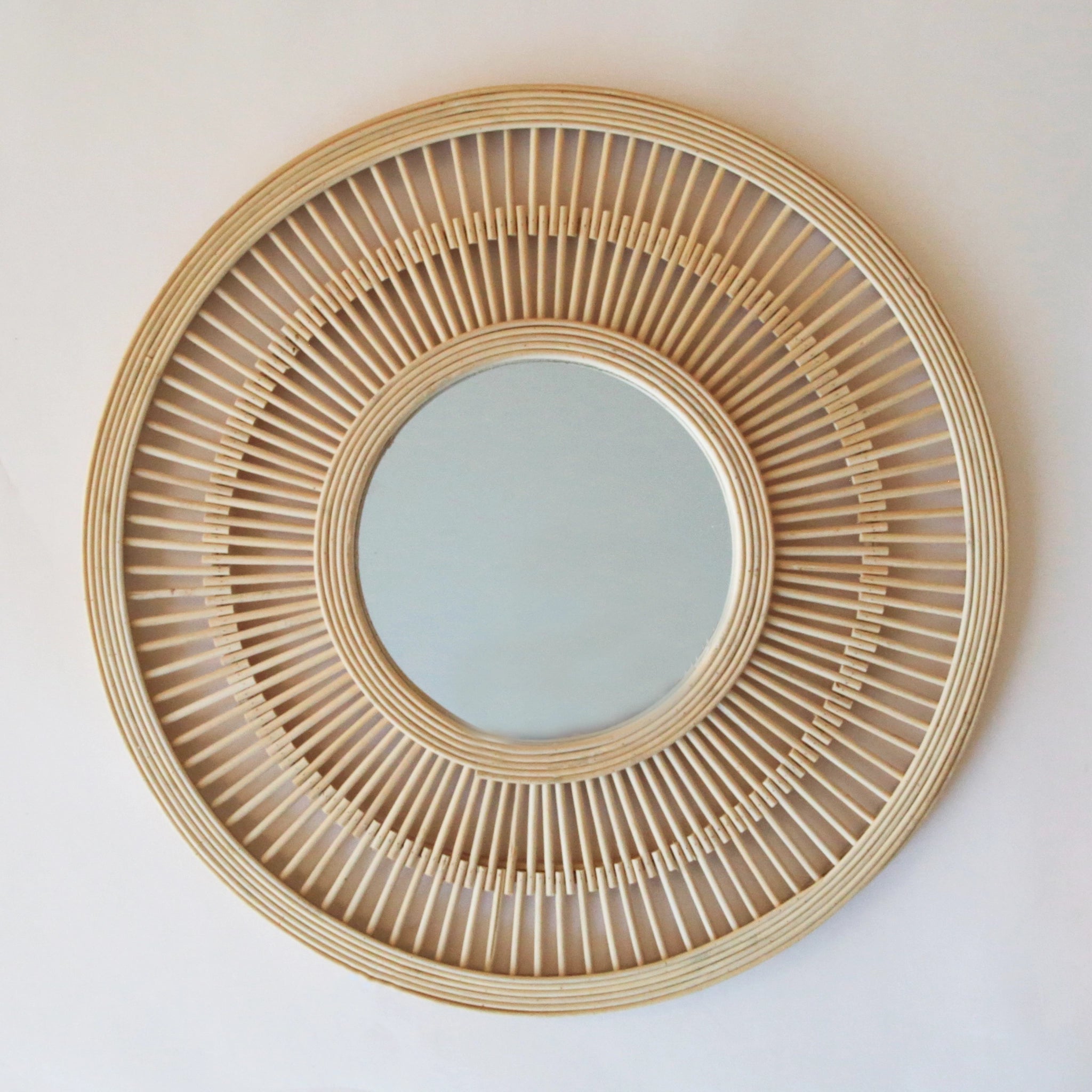 A circle mirror with a bamboo framing and a small round mirror in the center.
