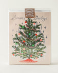 A cream colored card sits inside a clear, plastic case. The case is sitting against a white background. On the front of the card there is a drawing of a dark green Christmas tree. There are yellow and red Christmas lights up and down the tree. There are green, red and pink ornaments spread out all over the tree. Silver tinsel is hanging on the end of each tree branch. At the bottom is a red tree skirt. At the top is a sliver star. Above the tree in silver script it reads ‘season's greetings.’