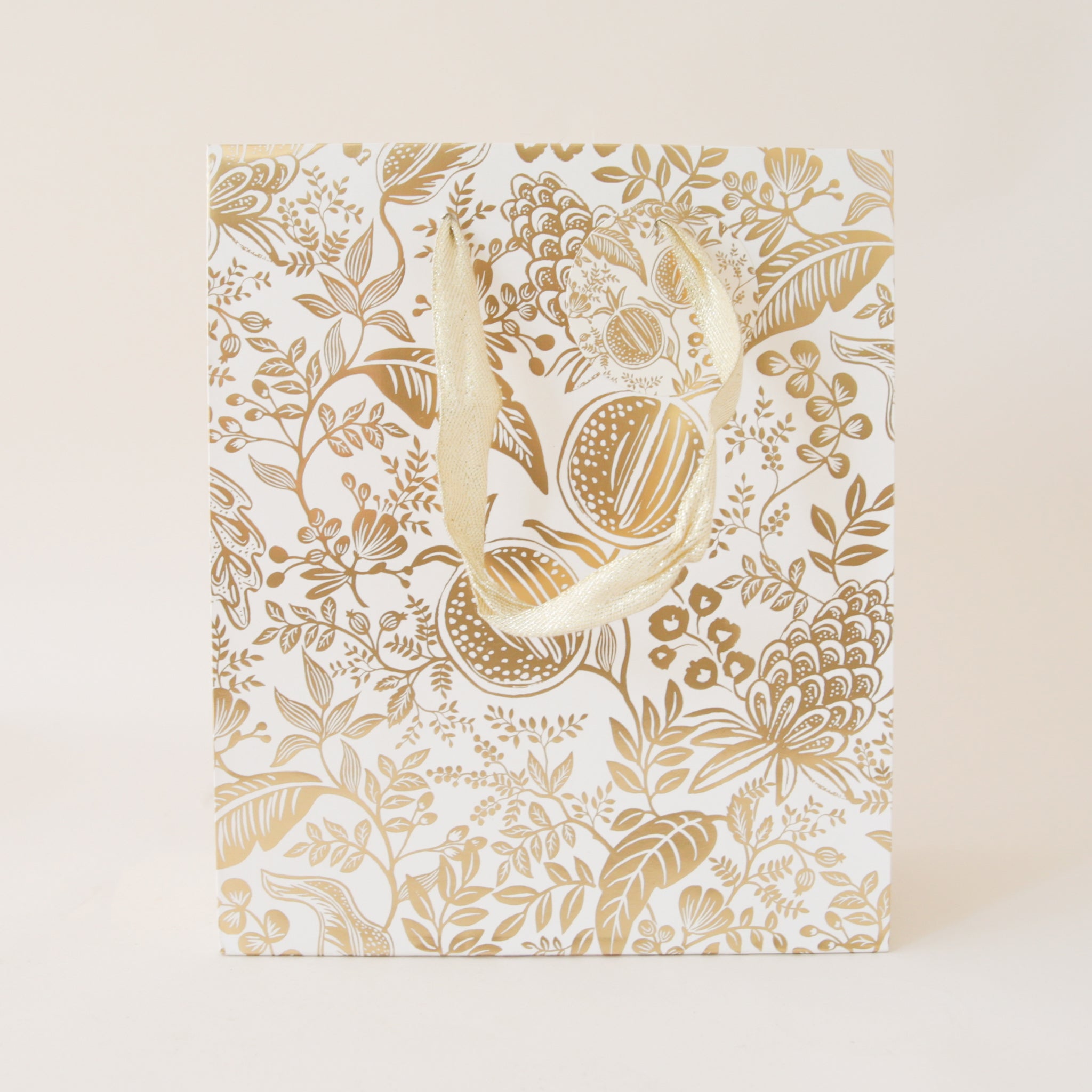 A gold foiled gift bag with metallic cotton handles and a to and from tag.