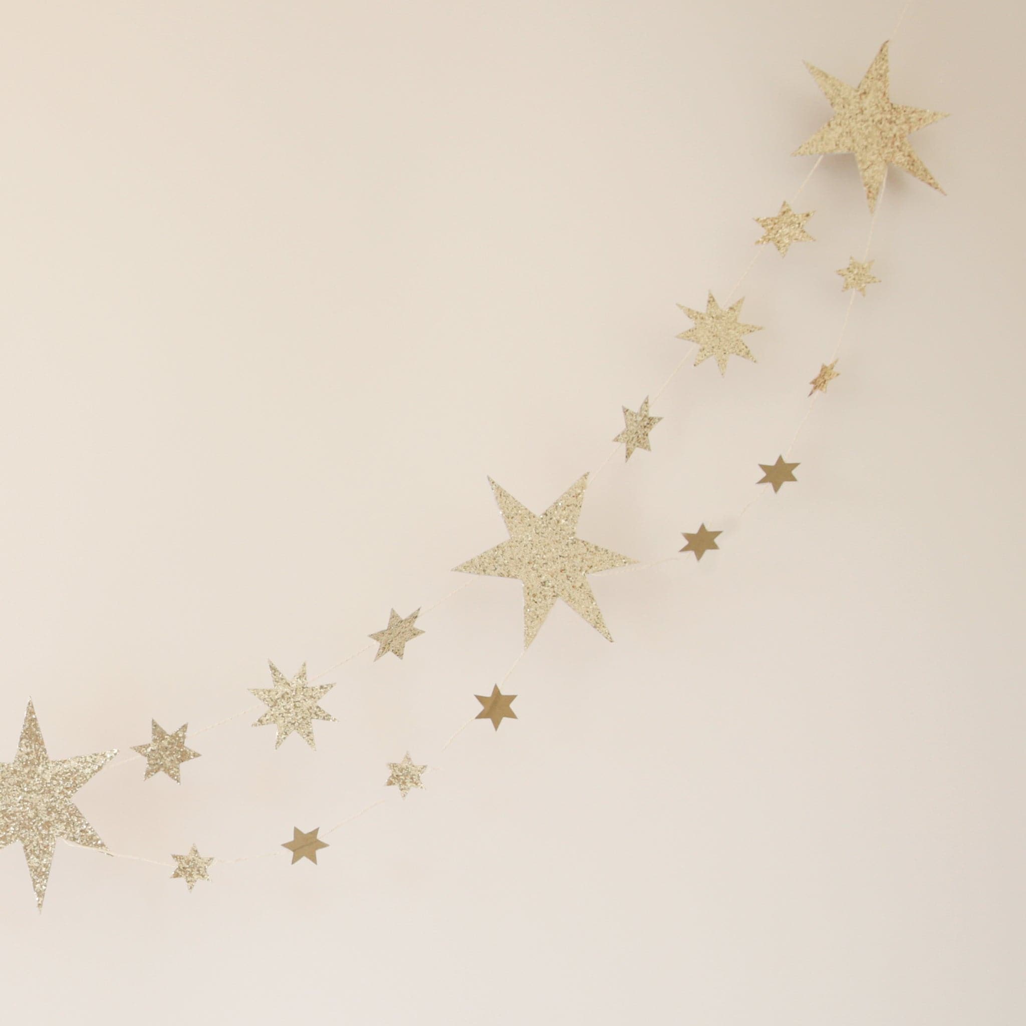 A double lined star garland made of thick paper along with chunky gold glitter on the front. The stars vary in size and alternate.