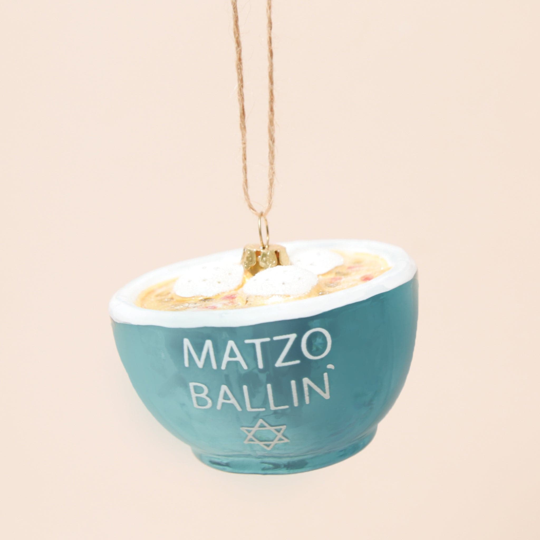 A glass matzo ball soup ornament with dumplings and a blue bowl that says "matzo ballin" in white text.