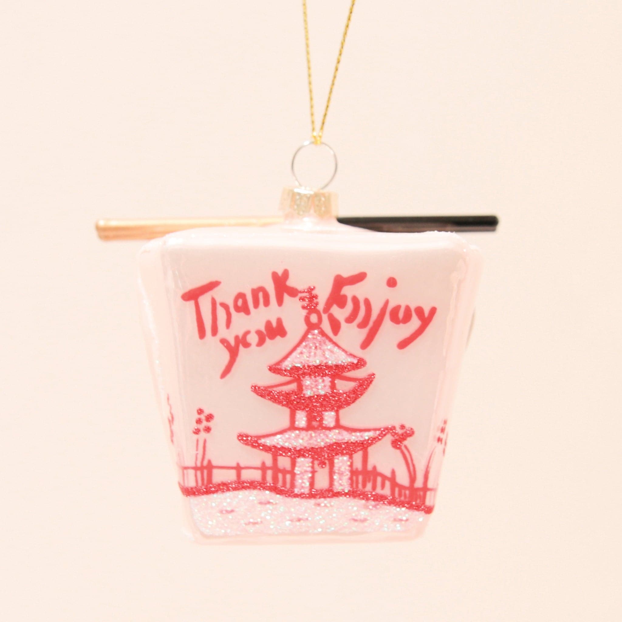A glass ornament made to look like a pink Chinese takeout box with a pair of chopsticks across the top.