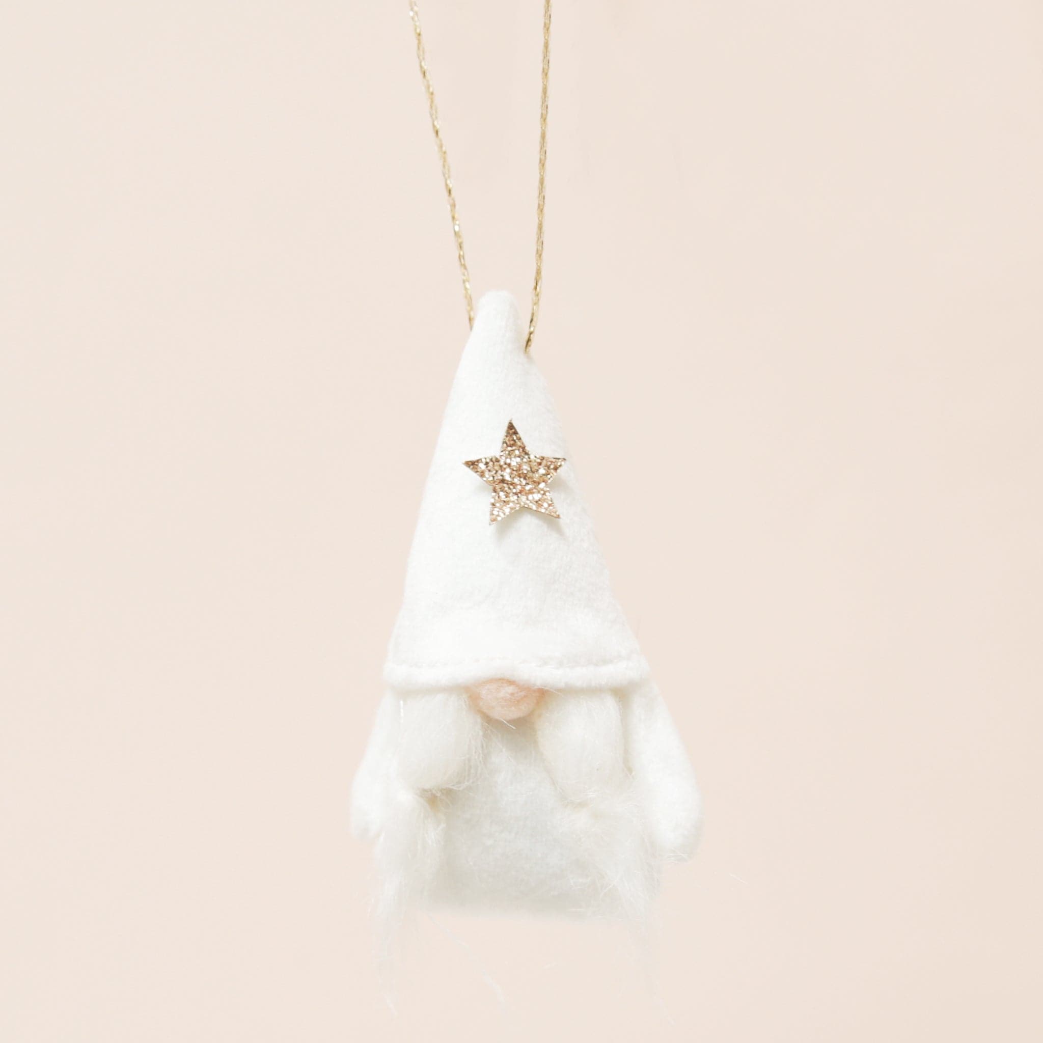 A plush white gnome ornament with a gold star and pigtail beard on a neutral ground.