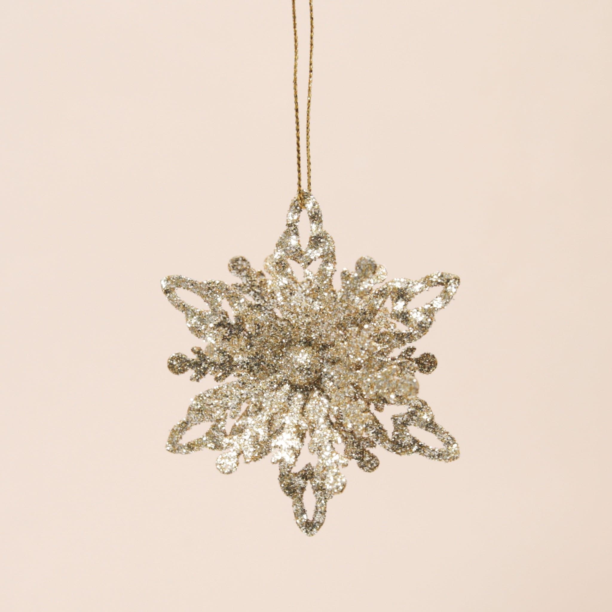 A gold metal snowflake ornament with intricate detailing. This is version three, which is a combination of the two previous options. I has a mix of open points and solid points.