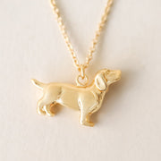 A dainty gold chain necklace with a small dachshund pendant.