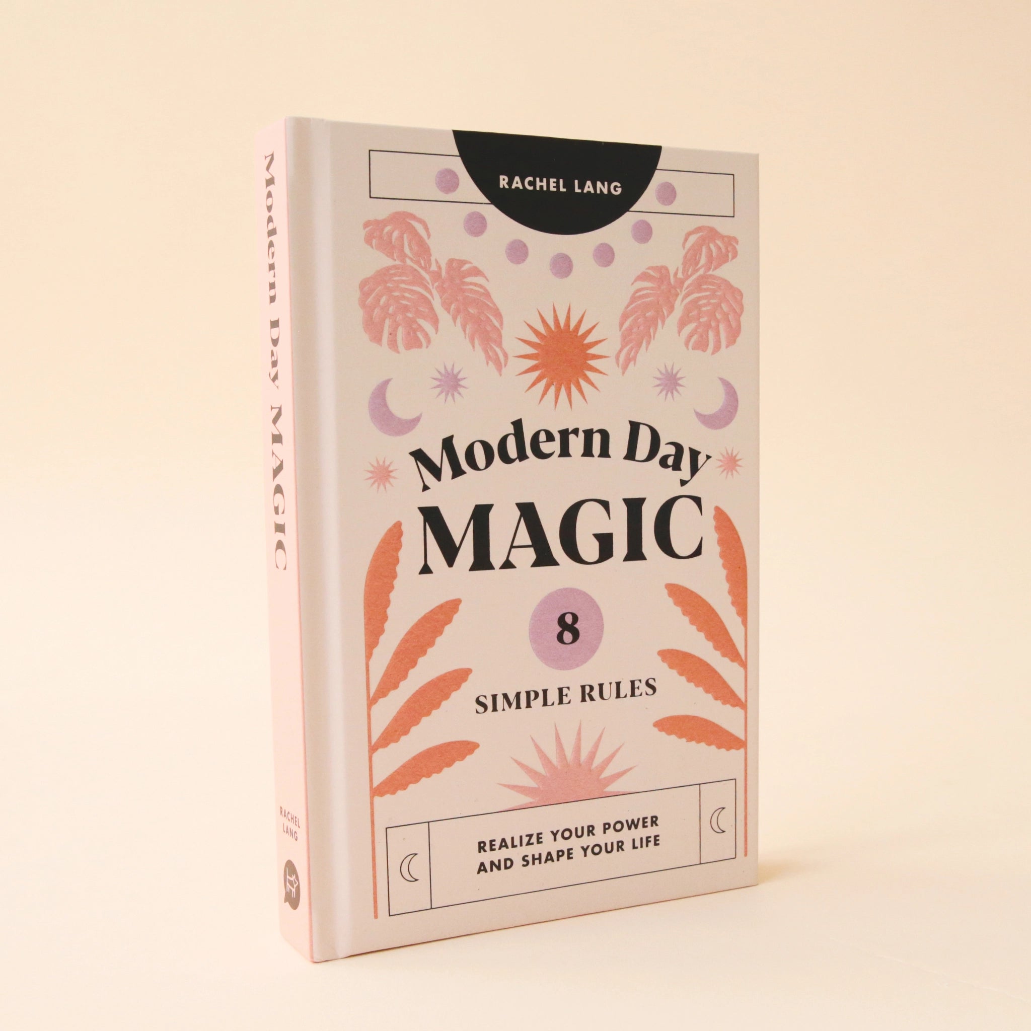 A light pink book cover with pink, lavender and orange foliage and sun and moon graphics along with black text that reads, "Modern Day Magic 8 Simple Rules Realize Your Power and Shape Your Life".