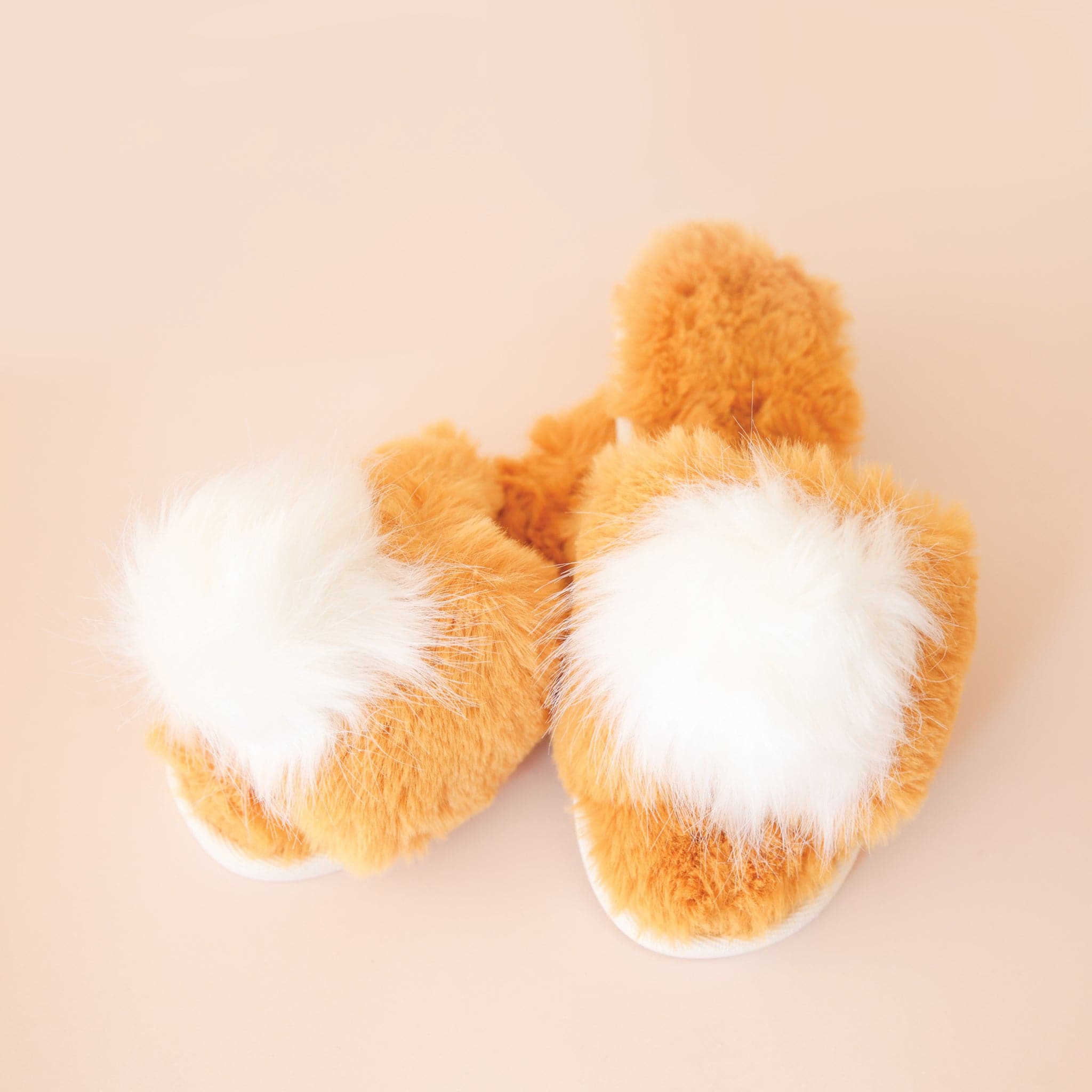 A yellow fuzzy slide on slipper with a white fuzzy pom pom on the center of each.