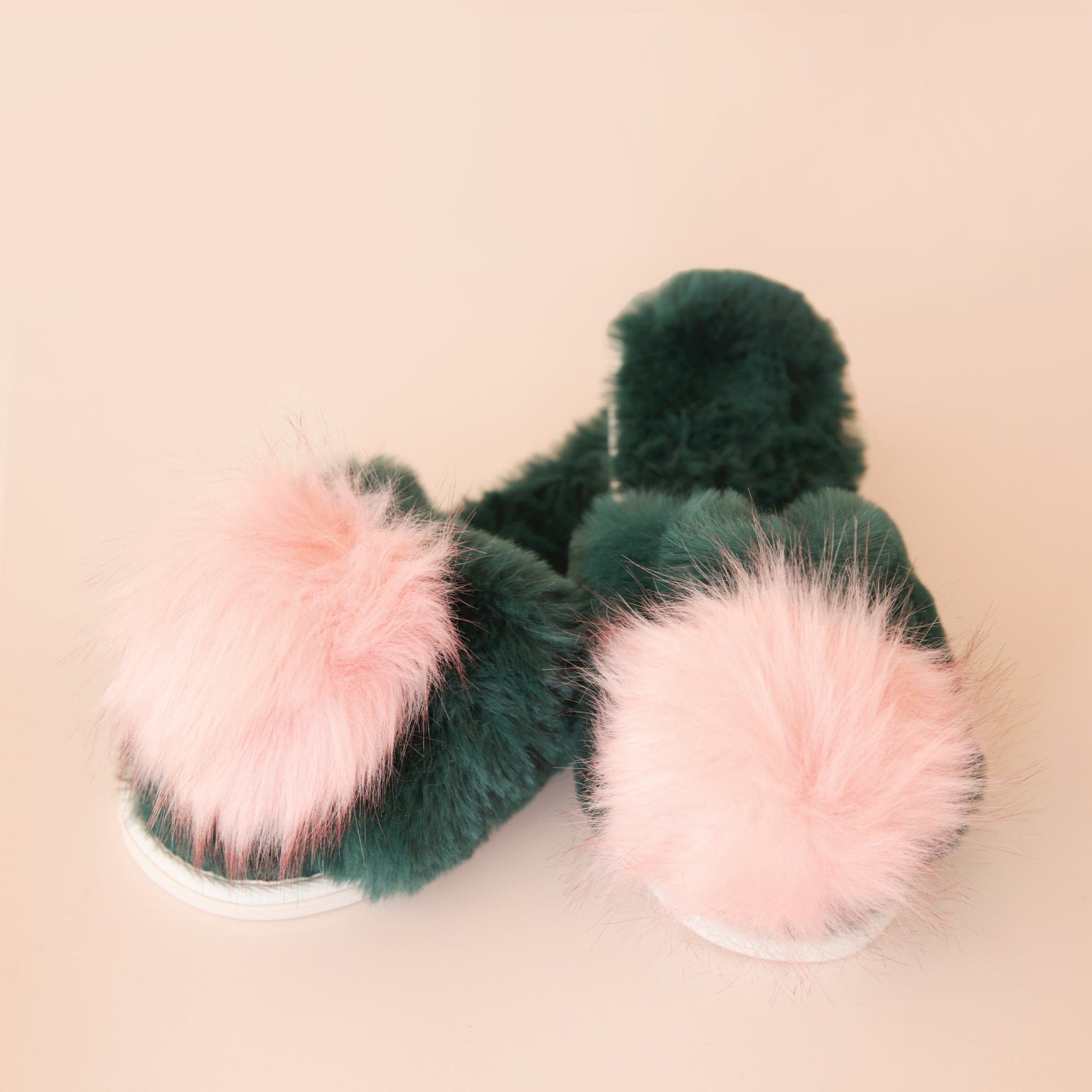 Green fuzzy slide on slippers with a pink fuzzy pom on the center of each one.