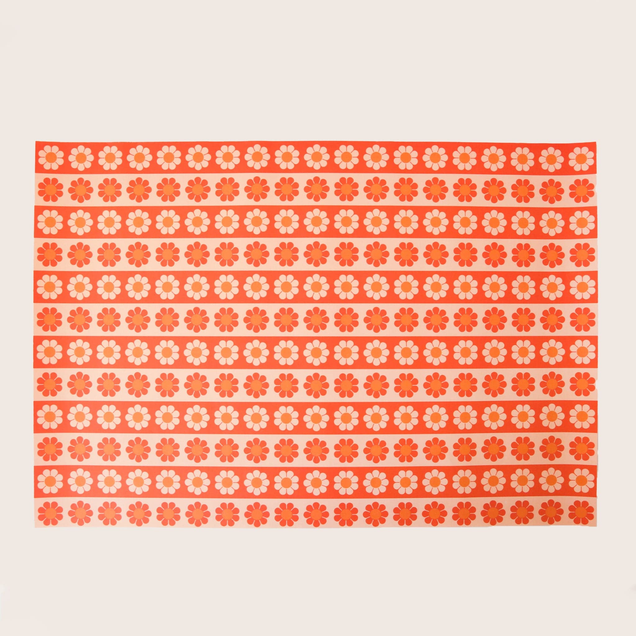 Wrapping paper with a  light yellow and orange and orange and red daisy pattern that alternates. 