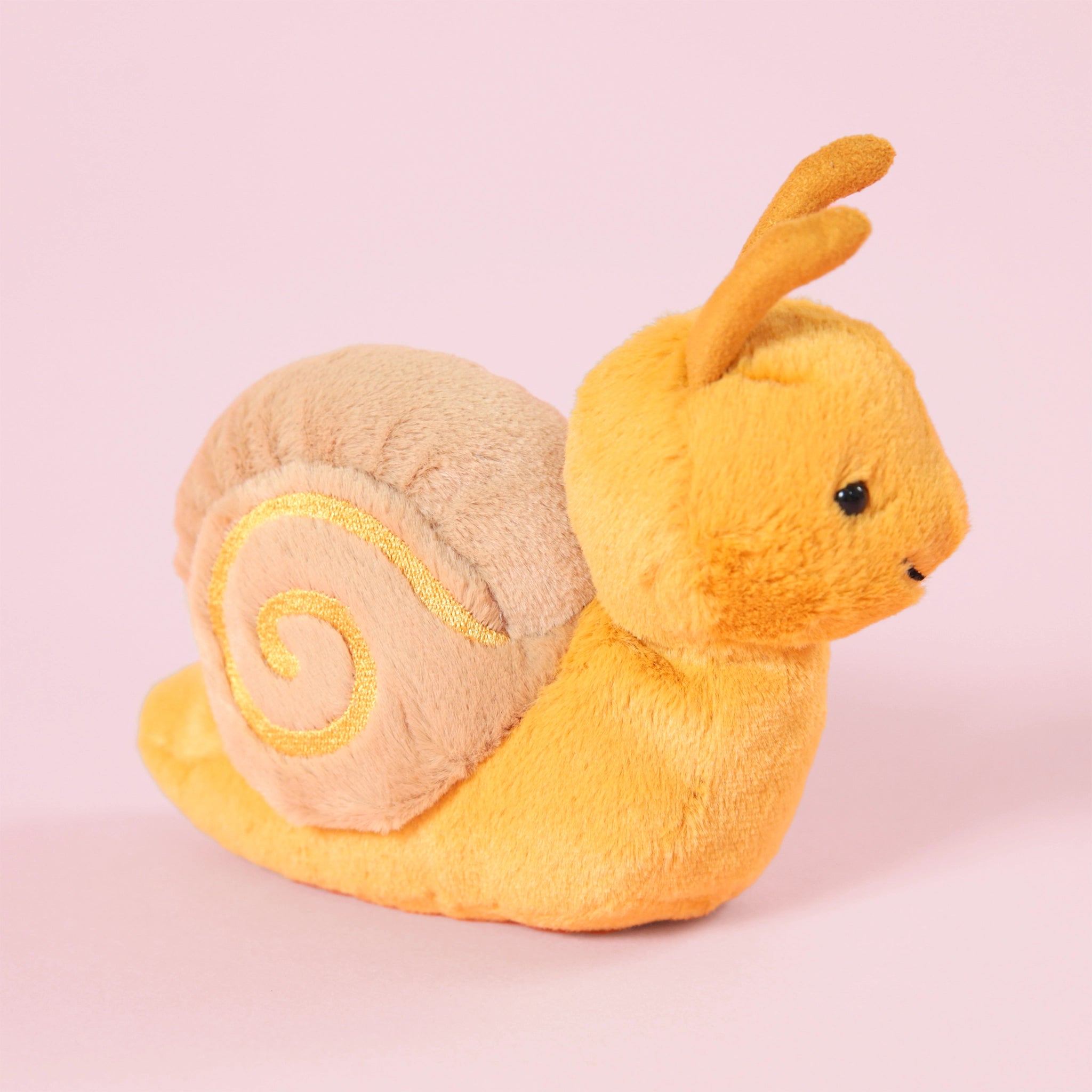 A yellow snail stuffed animal with a tan shell and a swirl design in the center.